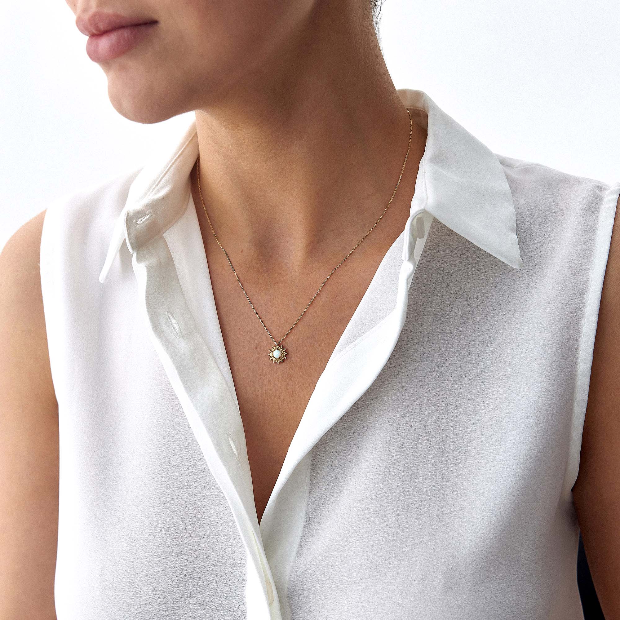 A model wearing a minimal sun necklace with a lab opal center