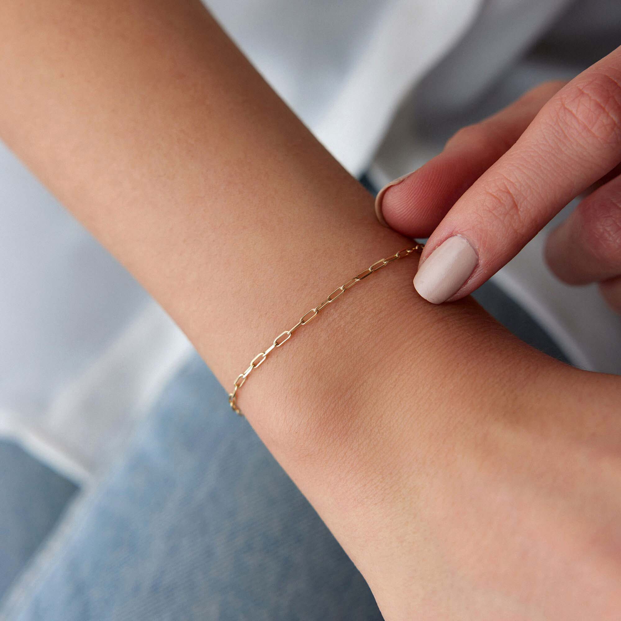 Minimal paperclip Gold chain bracelet on a wrist with a neutral background