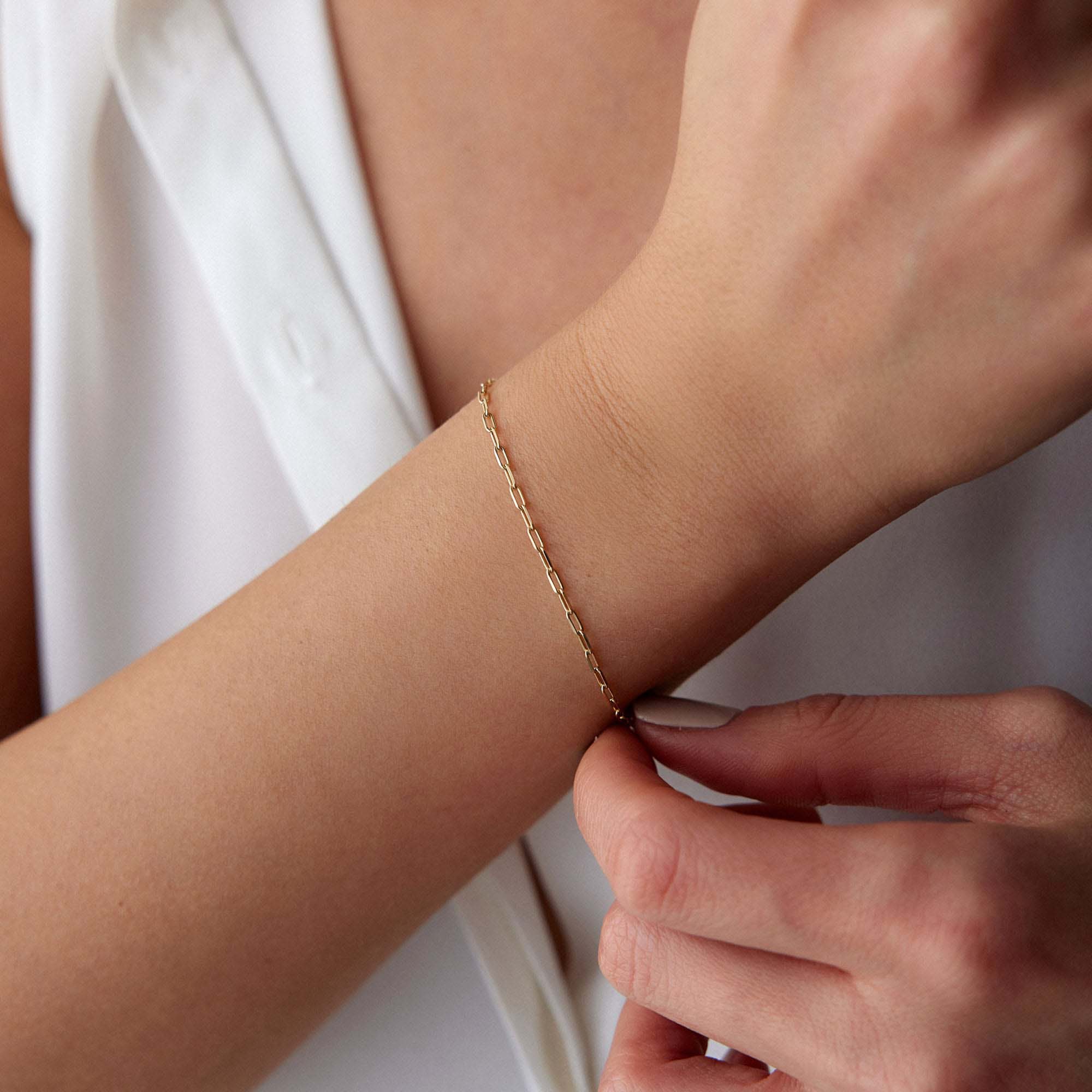 Minimal paperclip Gold chain bracelet on a wrist with a neutral background