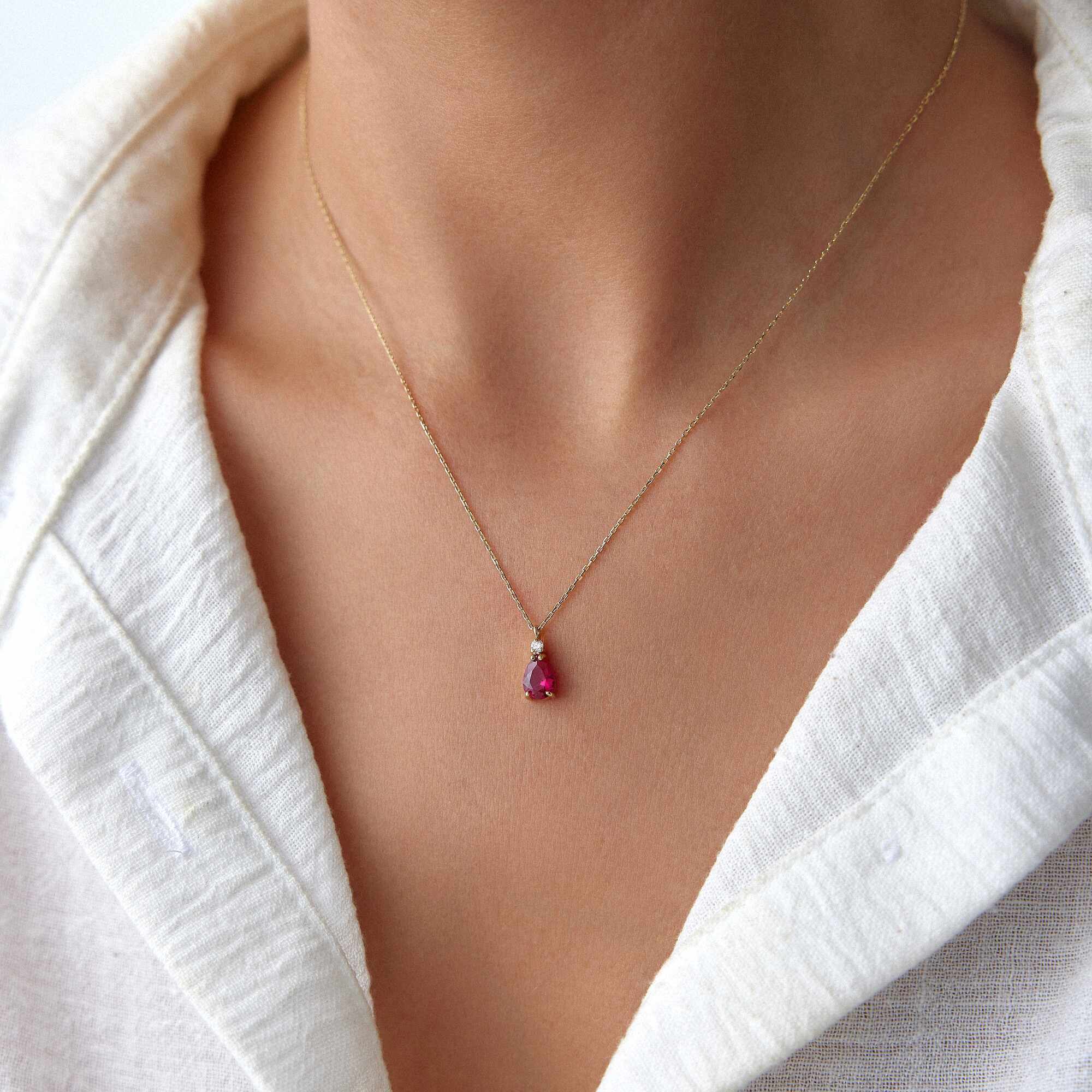 A model wearing a red drop necklace shown up-close.