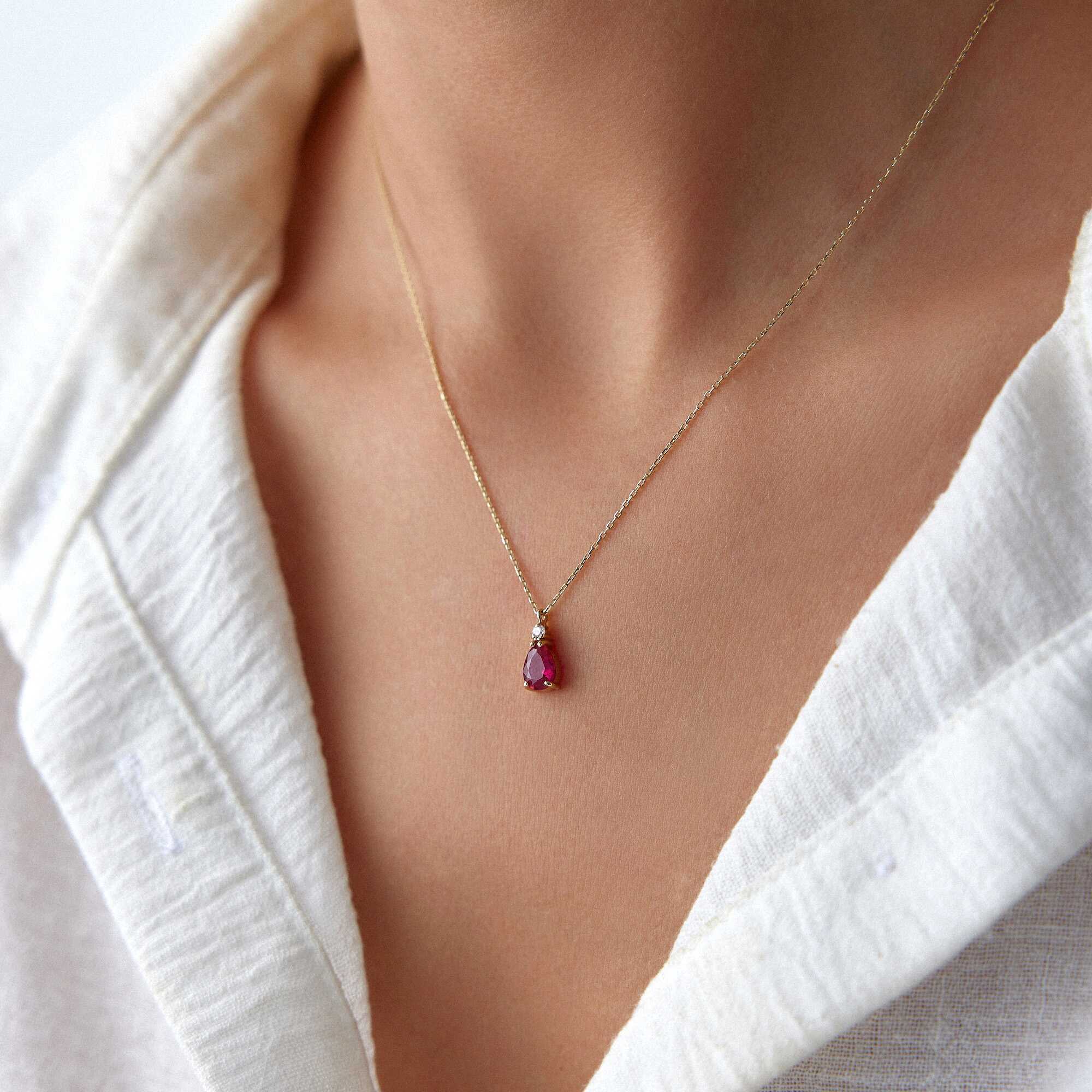 A model wearing a red drop necklace shown up-close.