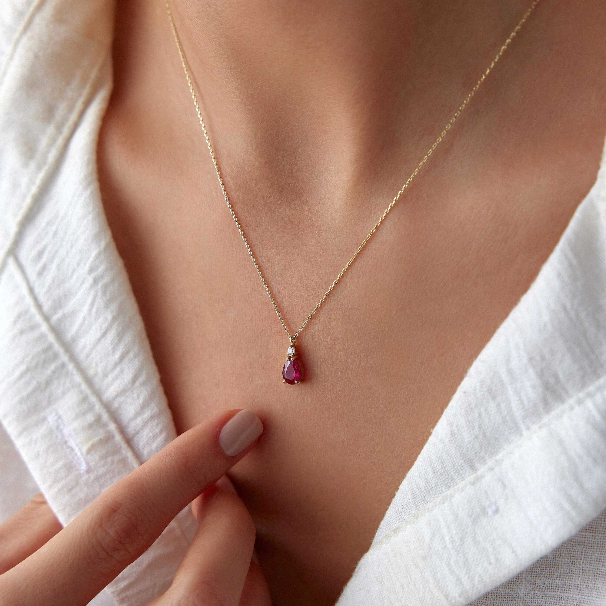 A model wearing a red drop necklace shown up-close.