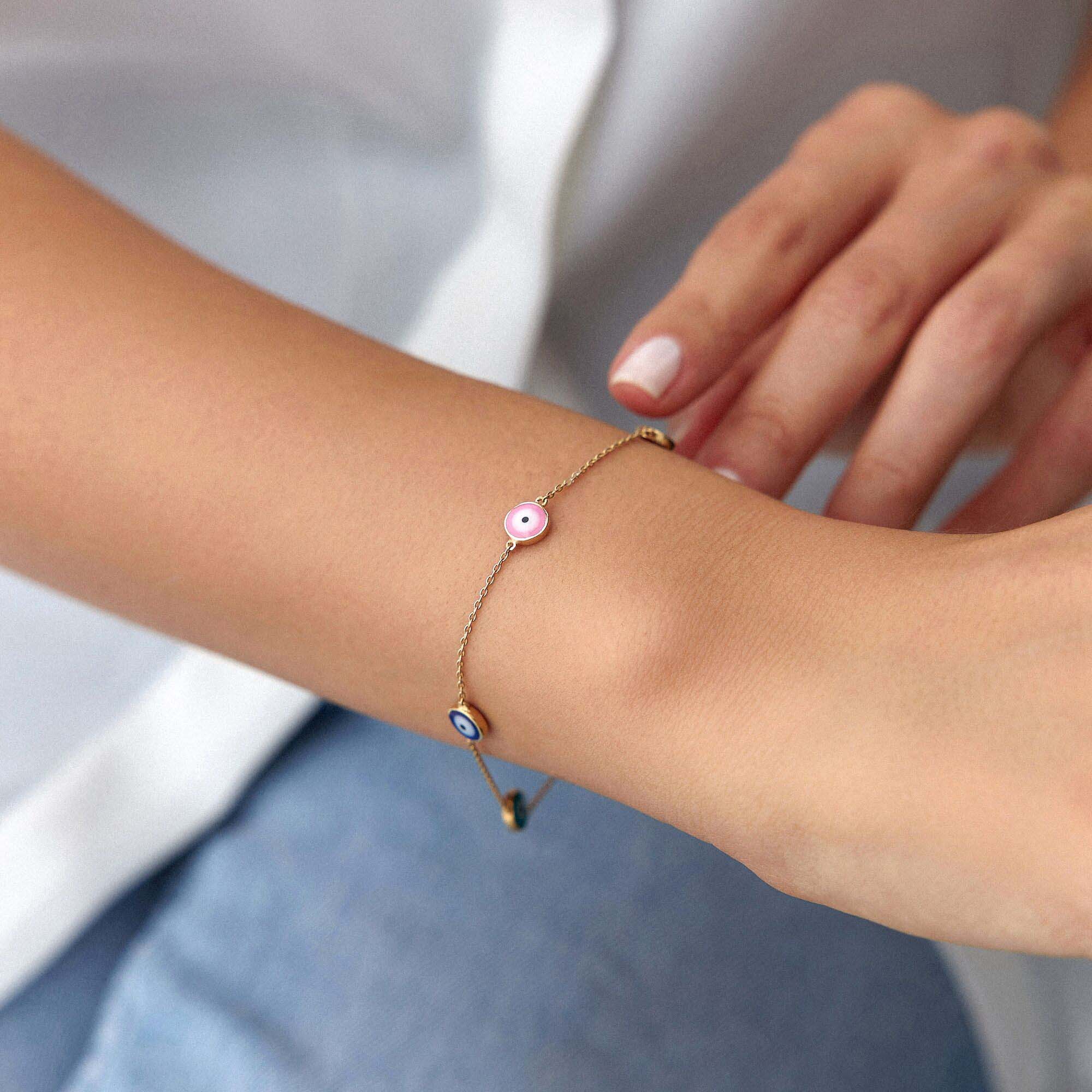 A 14K gold bracelet featuring multiple multicolored evil eye charms on a chain.
