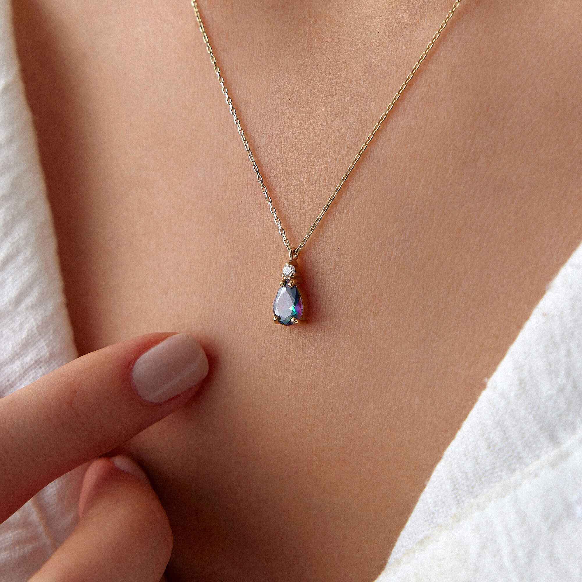 A close image of a model wearing a mystic topaz necklace