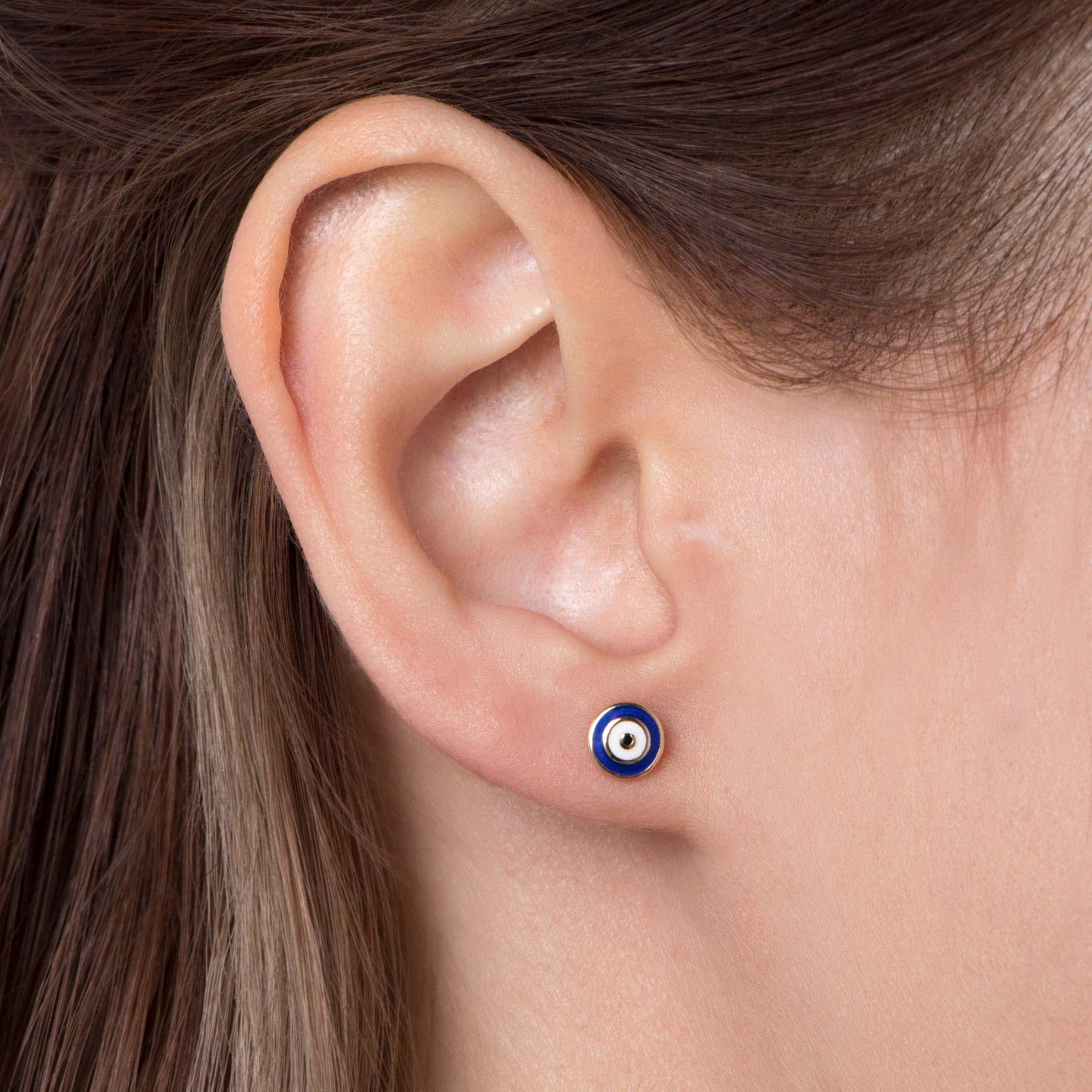 Close-up of an ear wearing a navy blueblue gold stud earring.