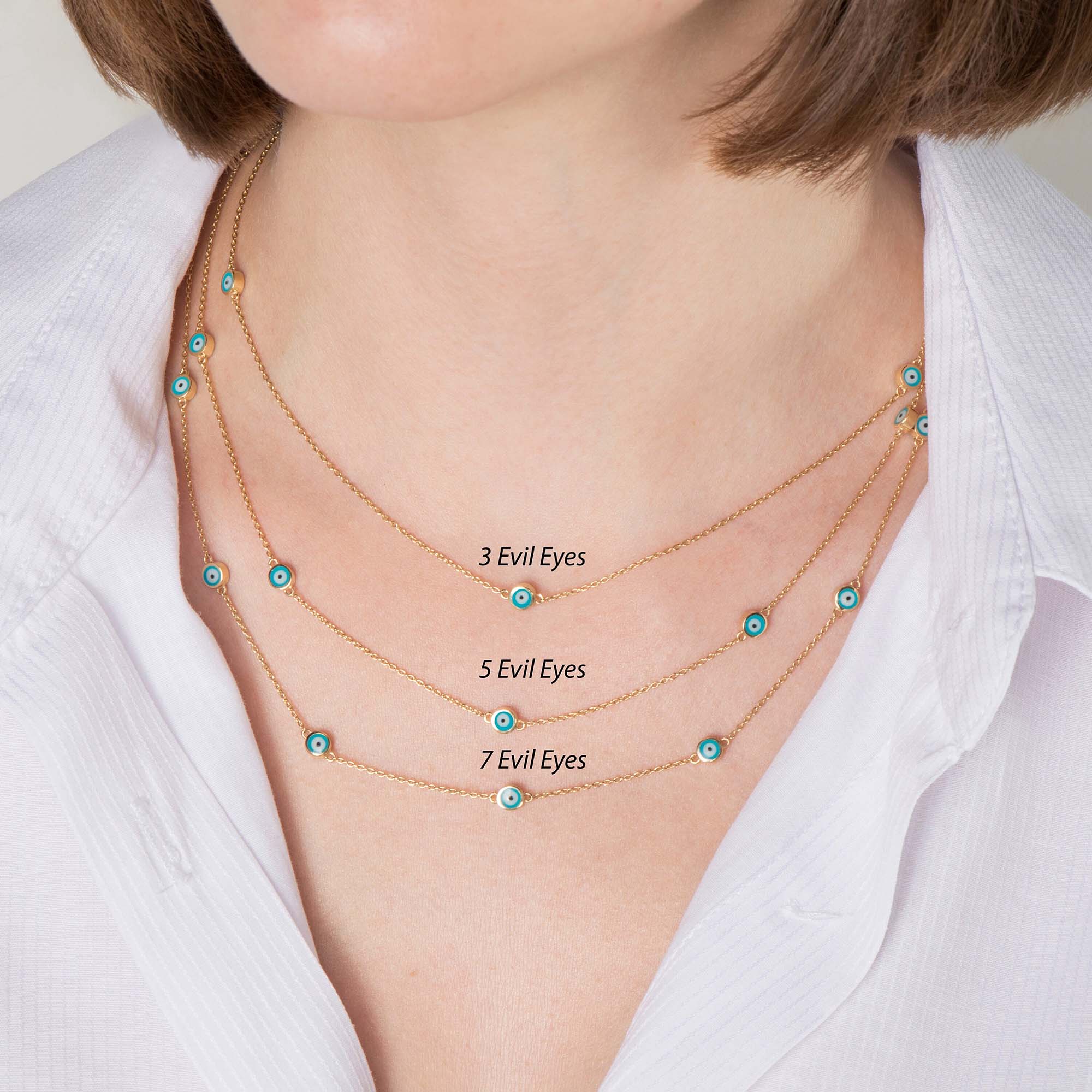 Three evil eye station necklaces shown layered up on a model. Top necklace features 3 ocean blue evil eyes, middle necklace features 5 ocean blue evil eyes, the bottom necklace features 7 ocean blue evil eyes.