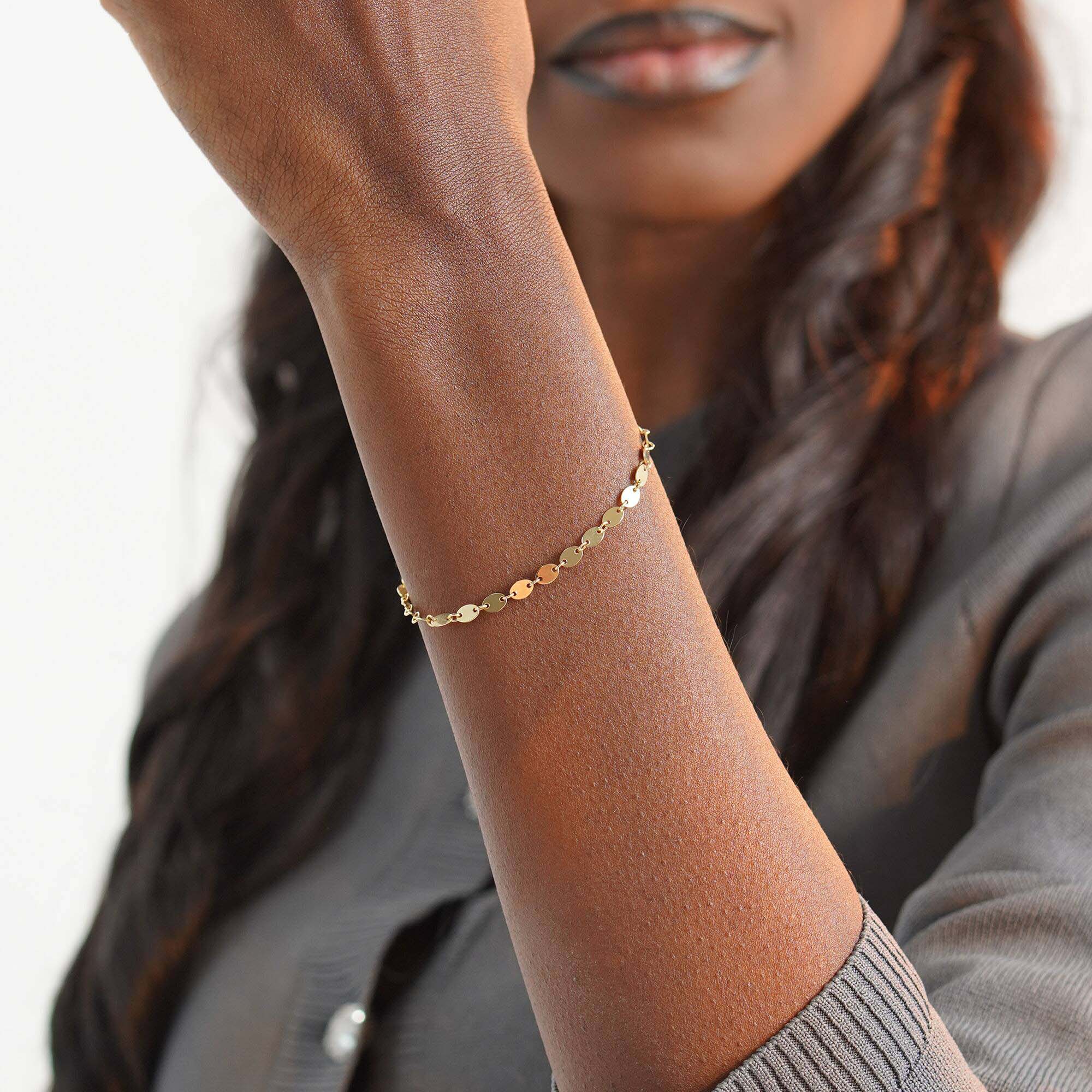 Woman wearing a gold bracelet on her wrist with a blurred background