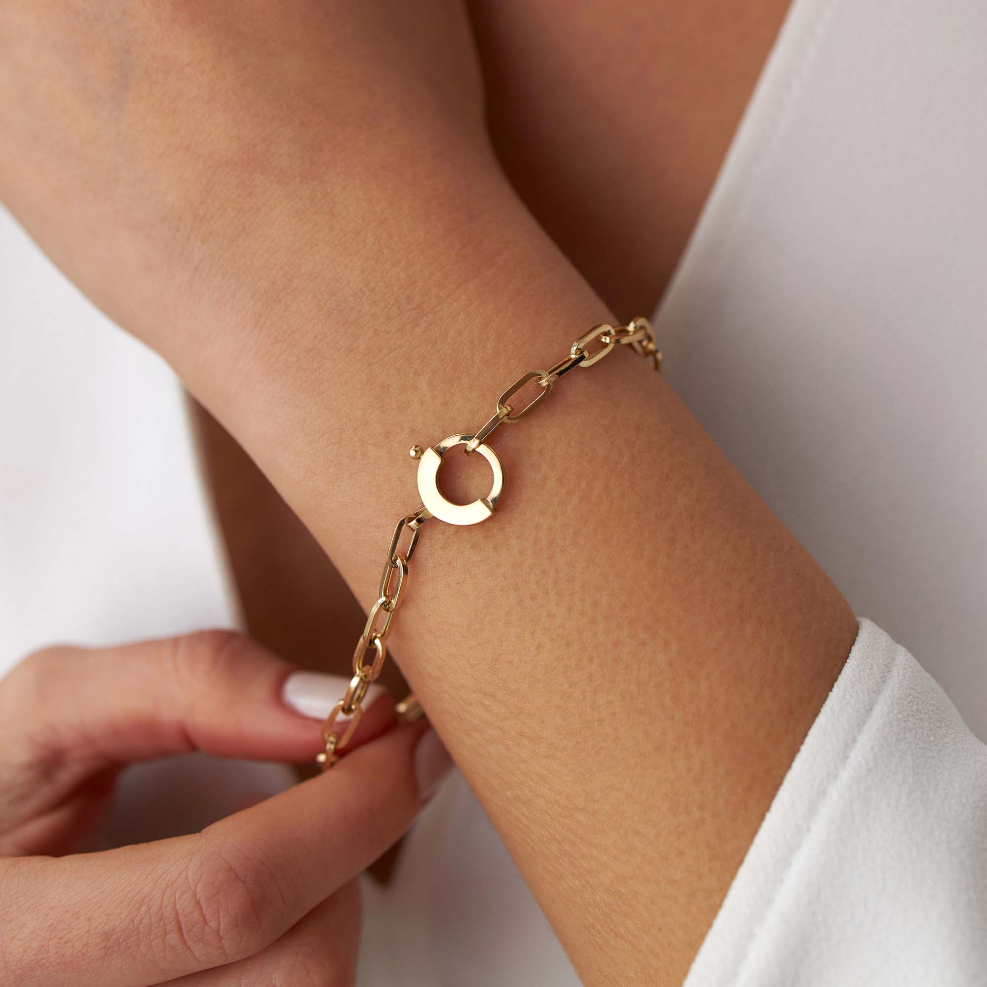 14k yellow gold paperclip chain bracelet with a special circular clasp shown on a wrist