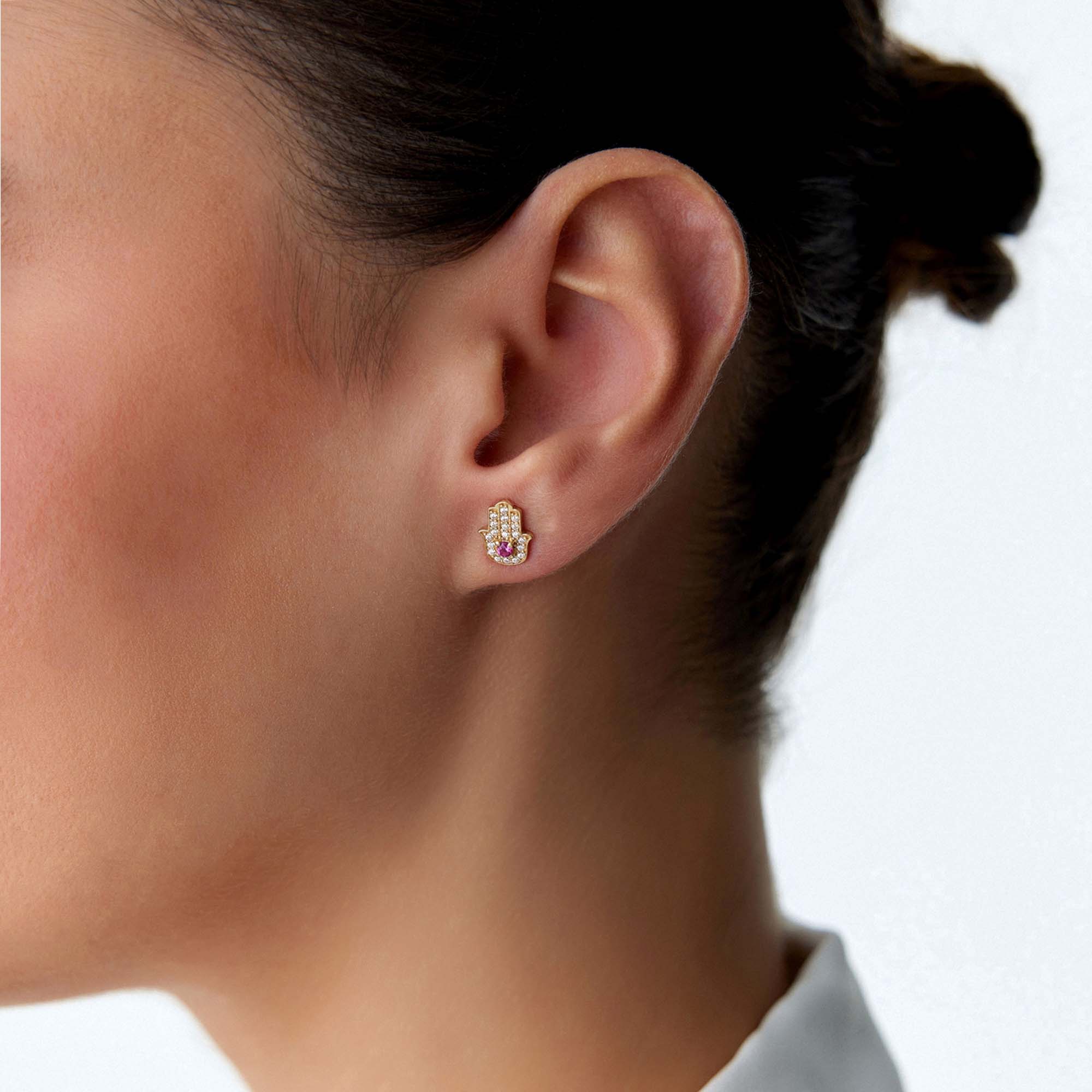 Close-up of an ear wearing a hamsa stud earring with a clear background