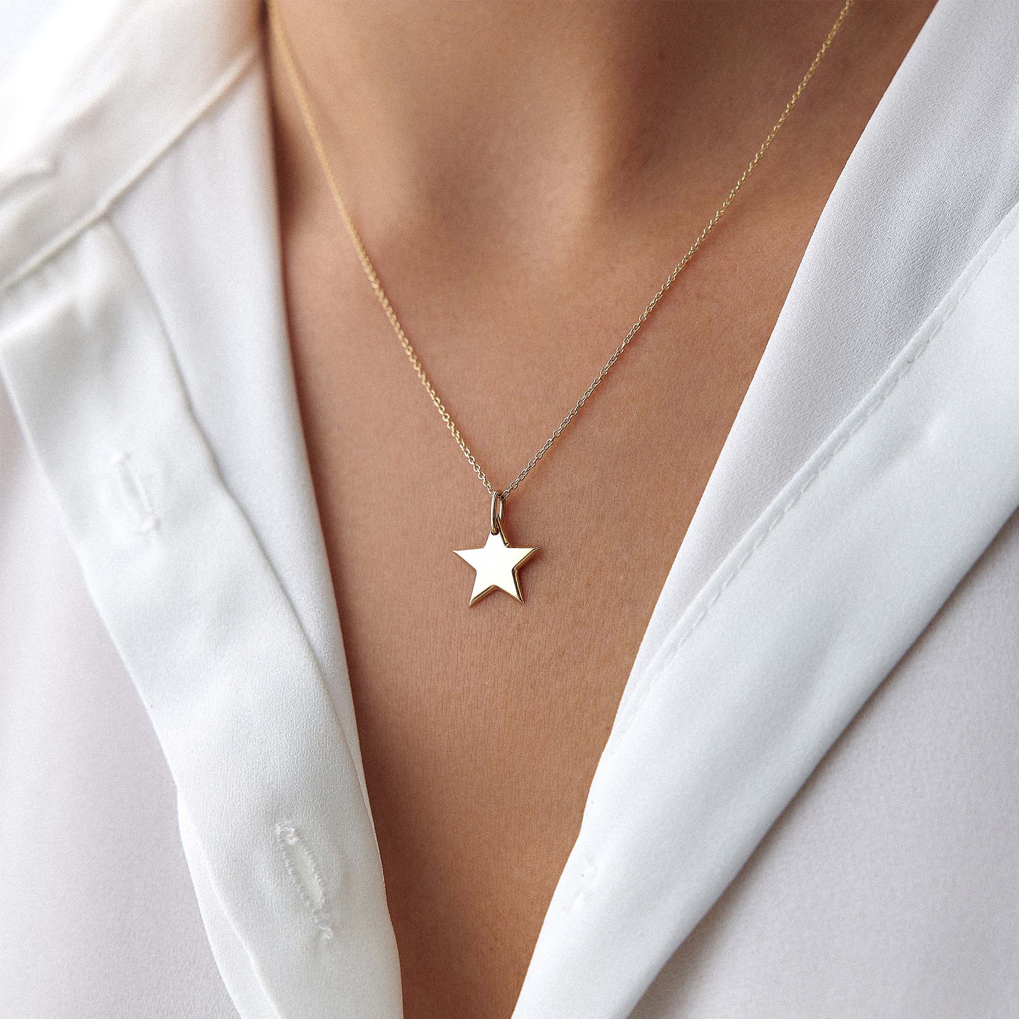 14k yellow gold star-shaped pendant necklace on a model wearing a white shirt