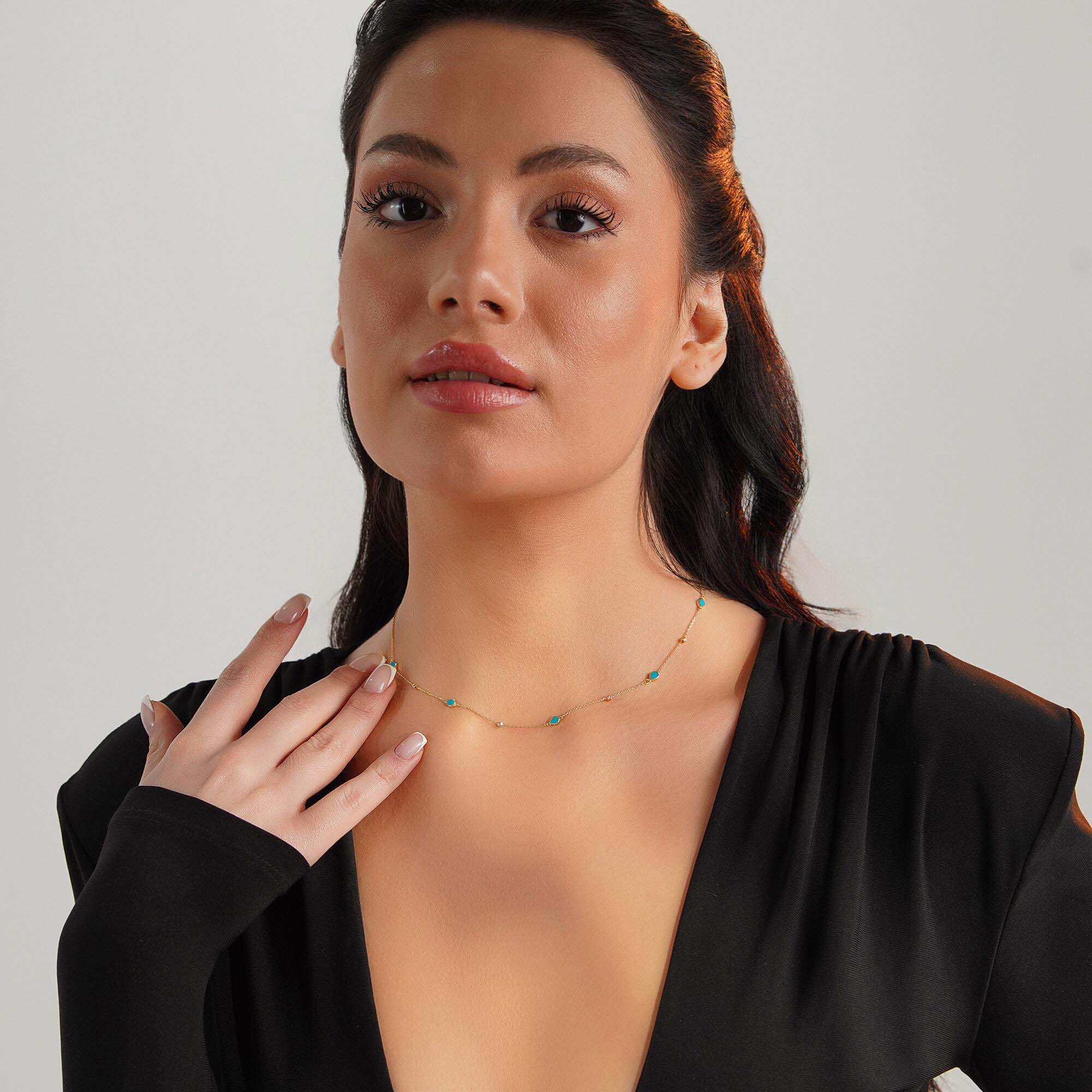 Woman wearing a raindrop station necklace against a neutral background