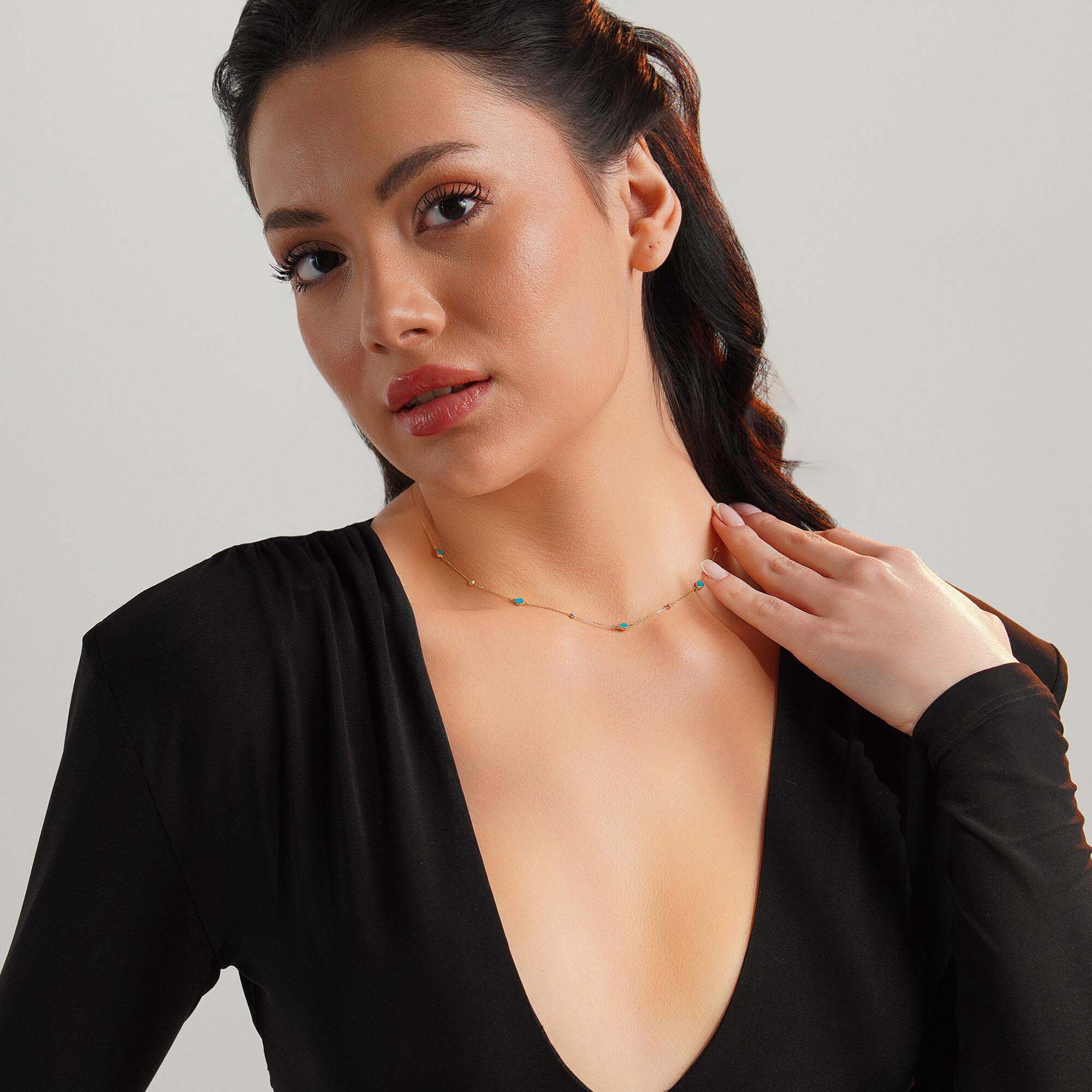 Woman wearing a raindrop station necklace against a neutral background