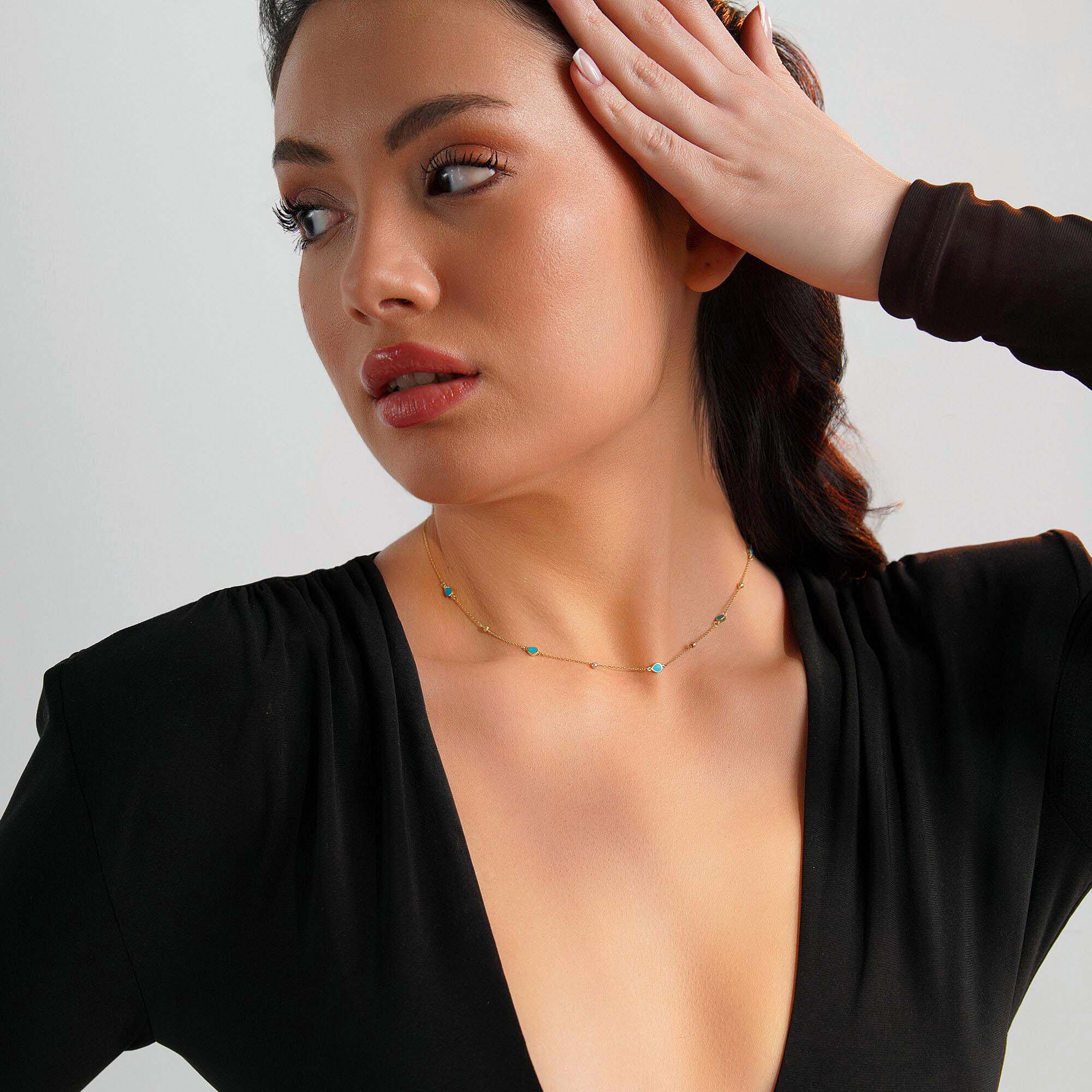 Woman wearing a raindrop station necklace against a neutral background