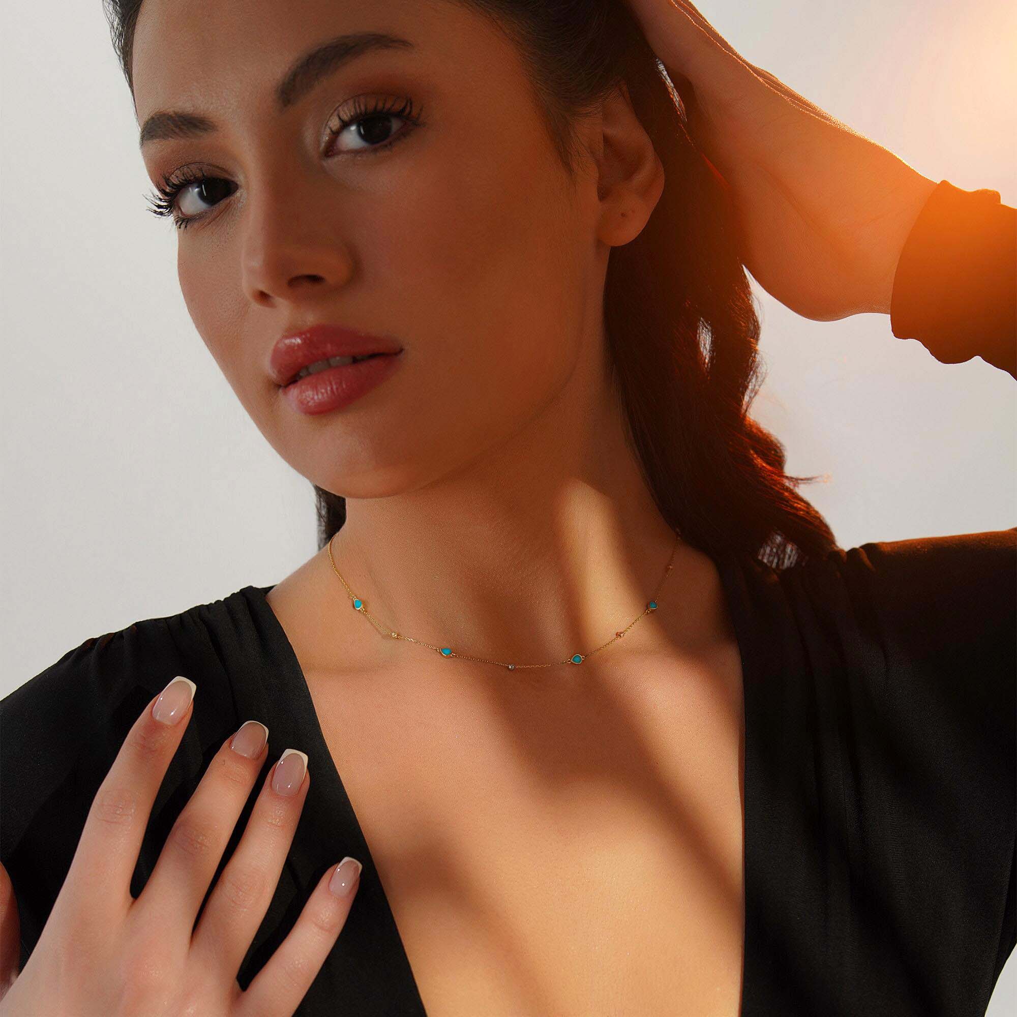 Woman wearing a raindrop station necklace against a neutral background