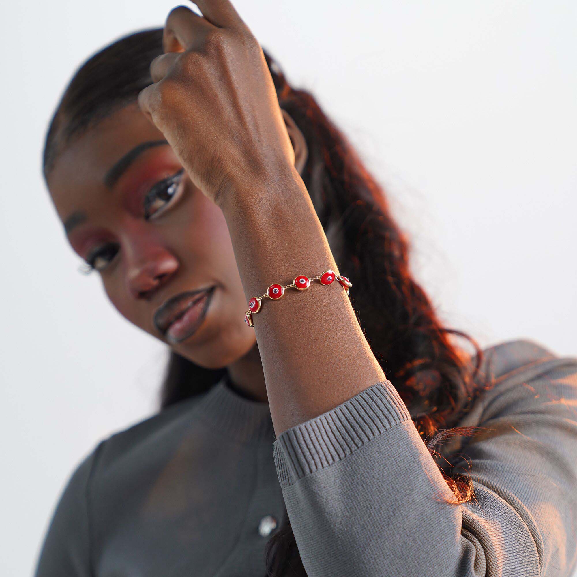 Woman wearing a red evil eye bracelet on a blurred background