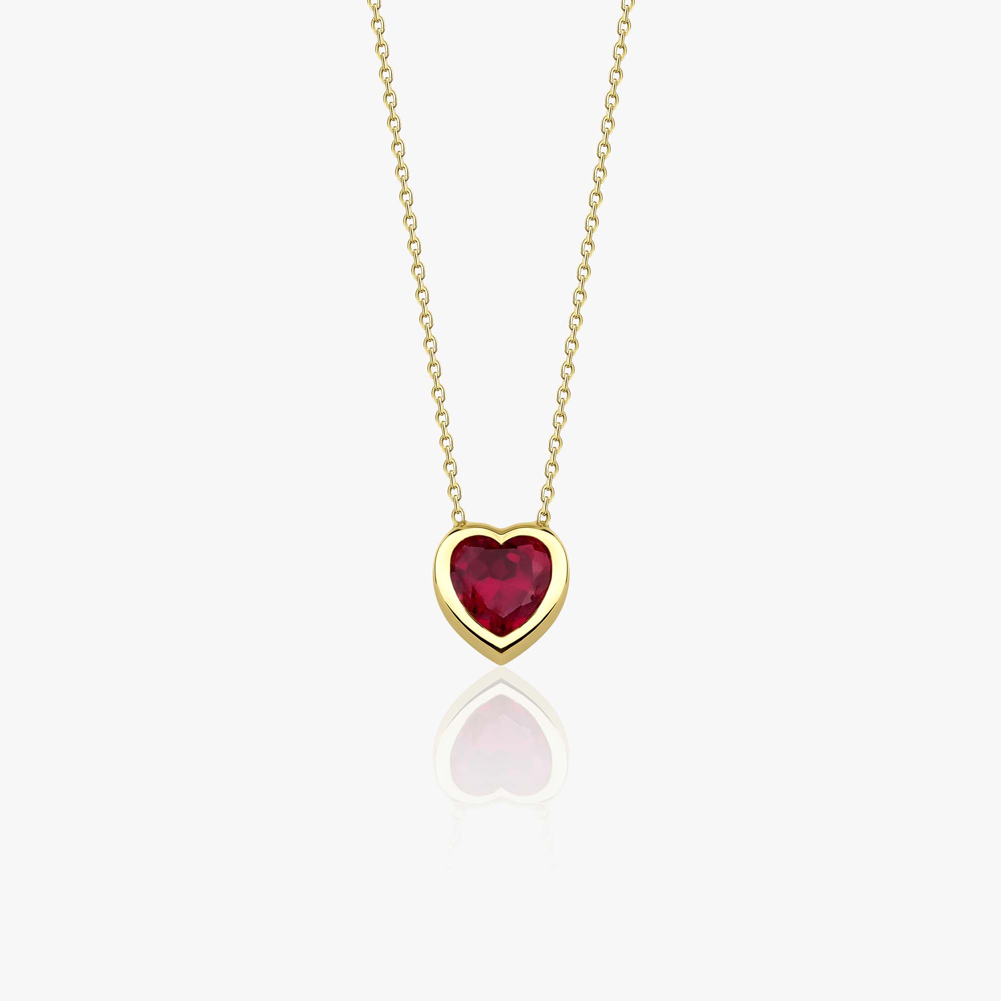Gold necklace with a heart-shaped red gemstone pendant on a white background