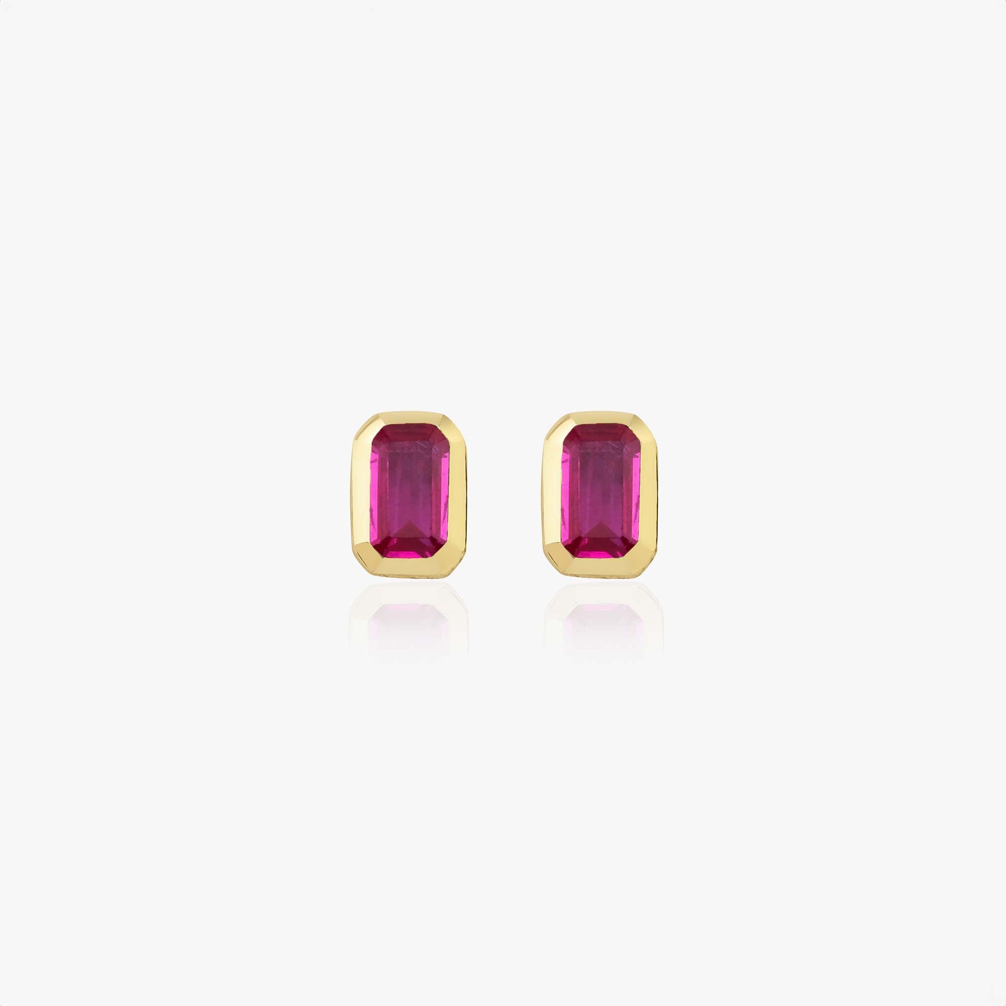 Pair of gold earrings with red gemstones on a white background