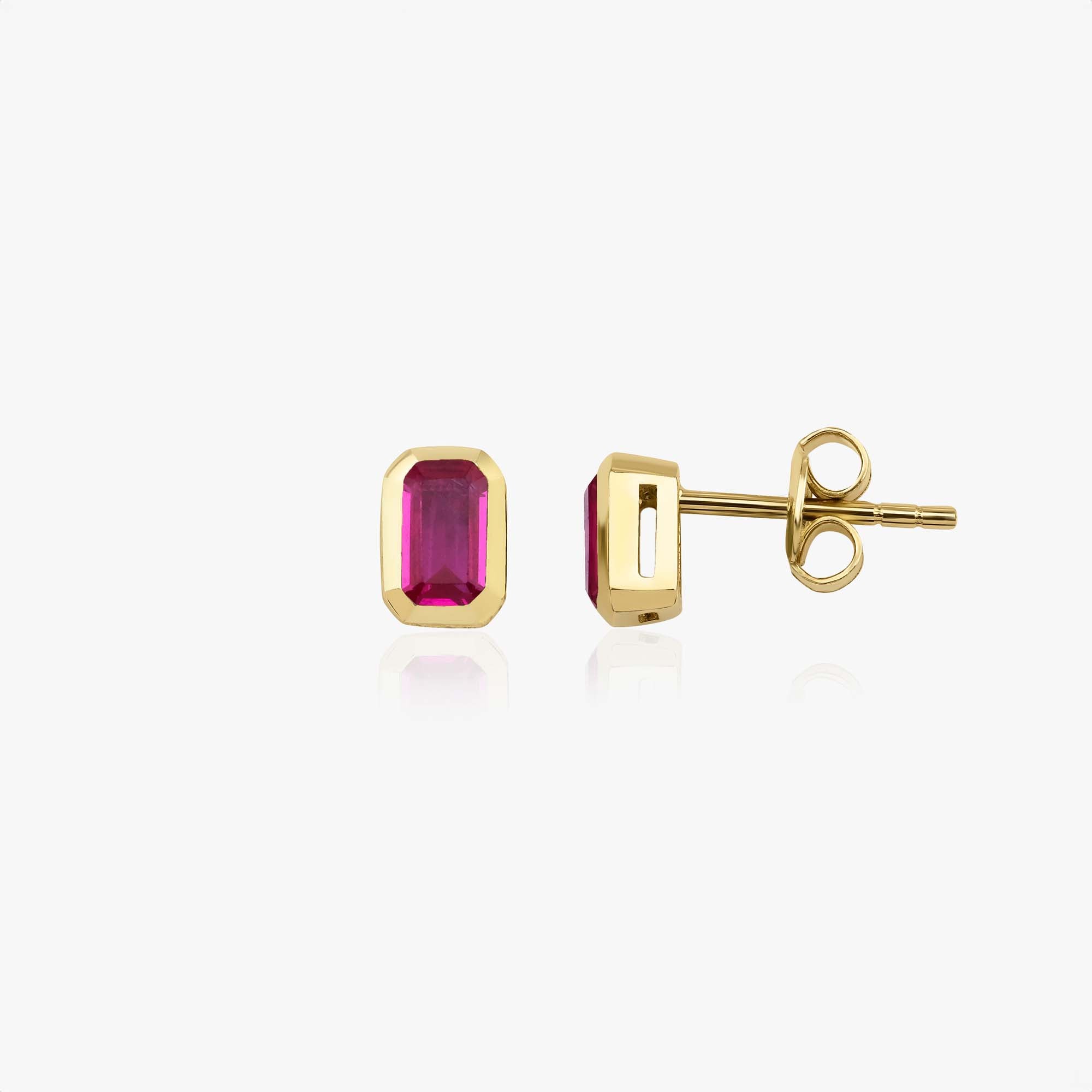 Gold earrings with pink gemstones on a white background, one shown sideways
