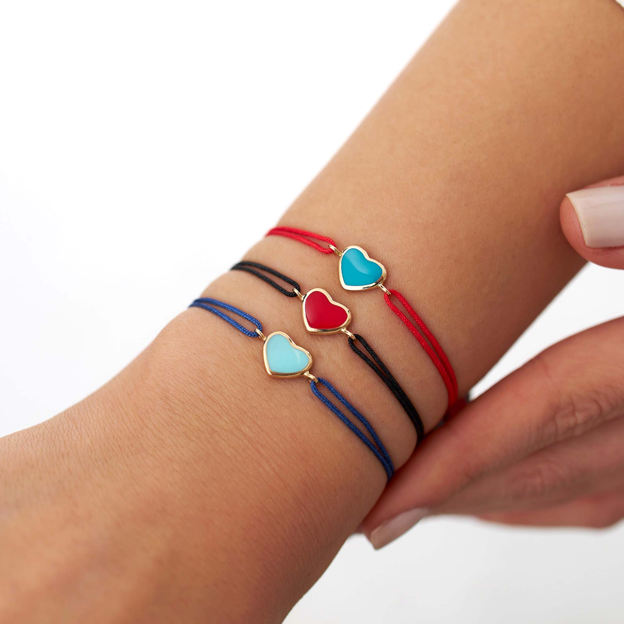 Bracelets with heart-shaped charms on a wrist against a white background