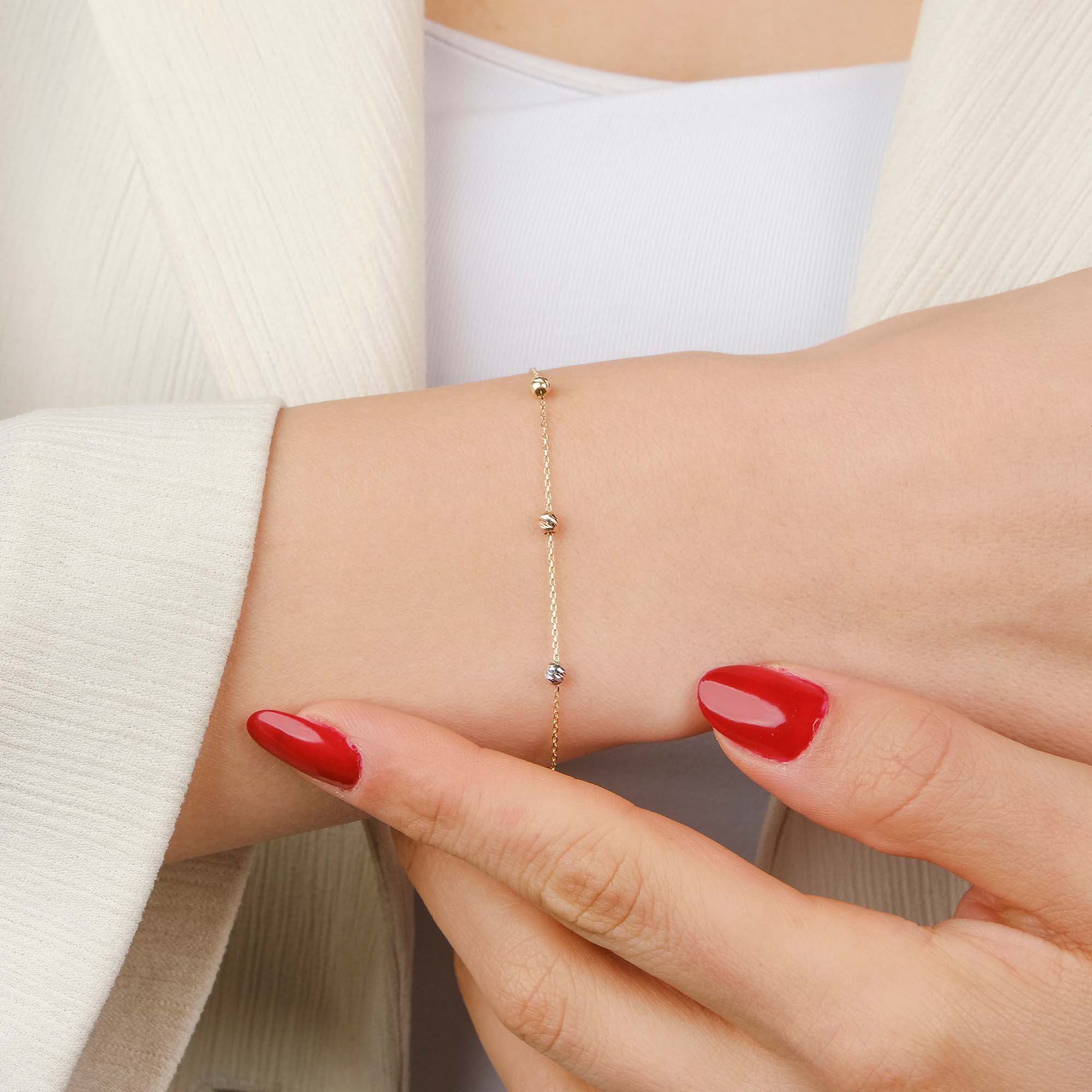 14k yellow gold tricolor beaded chain bracelet shown on a wrist