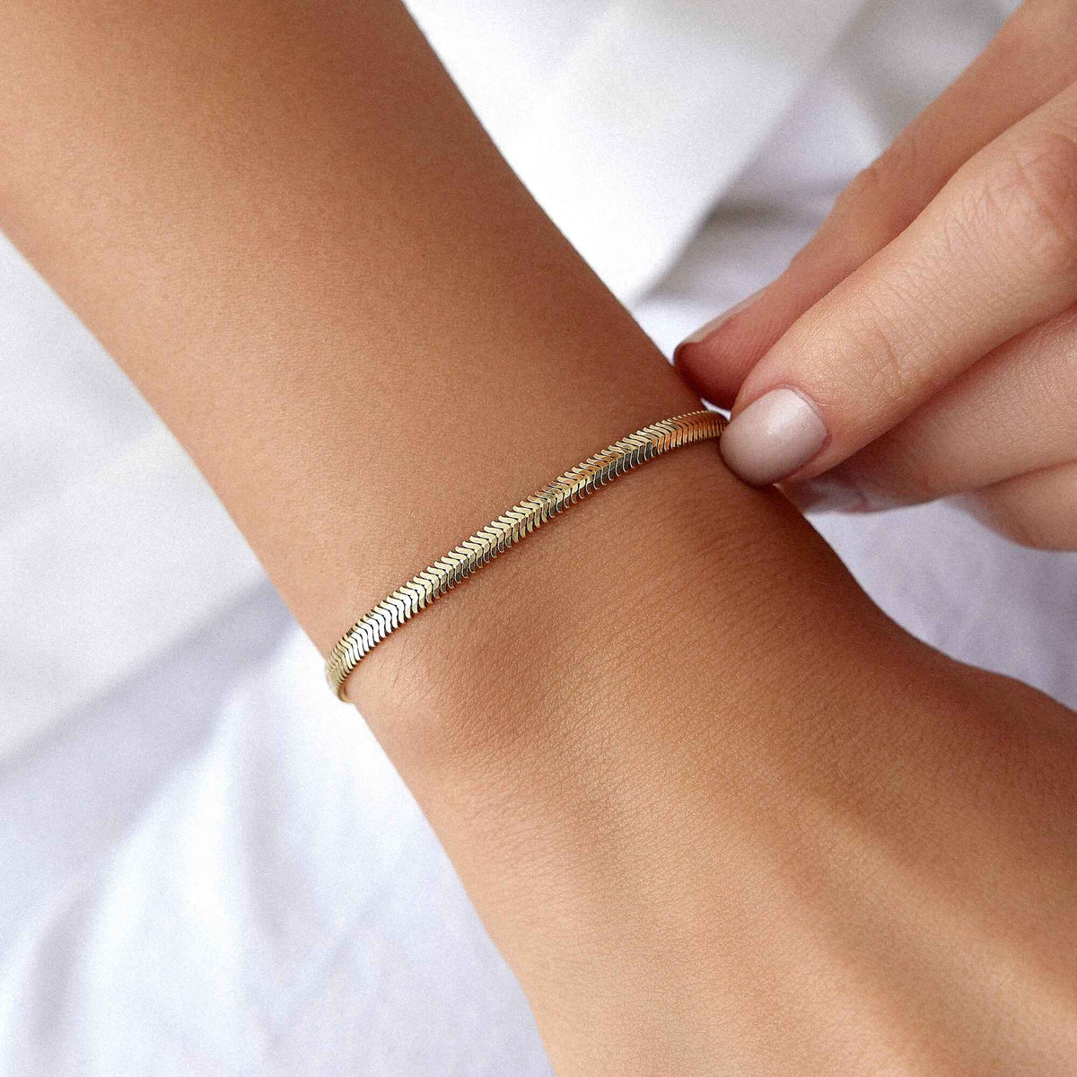 a model wearing a 14k solid gold snake chain on her wrist