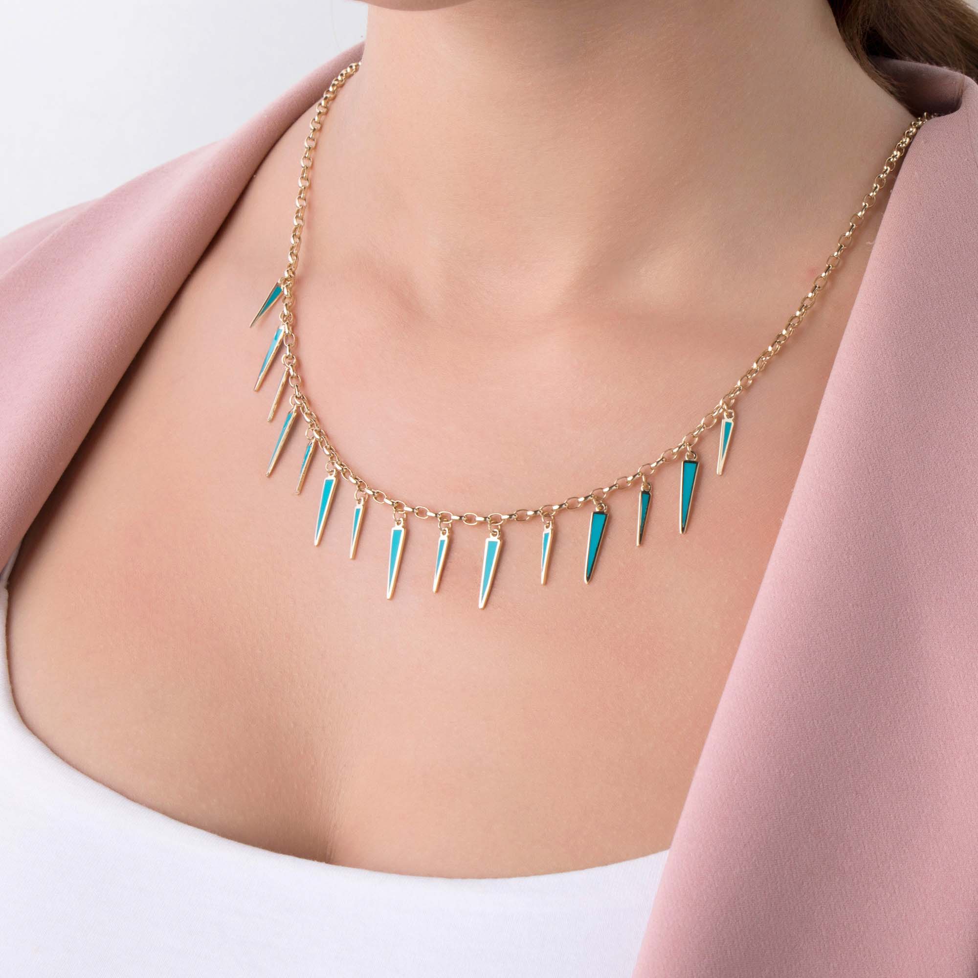 Necklace with turquoise and gold spikes on a person wearing a pink coat.