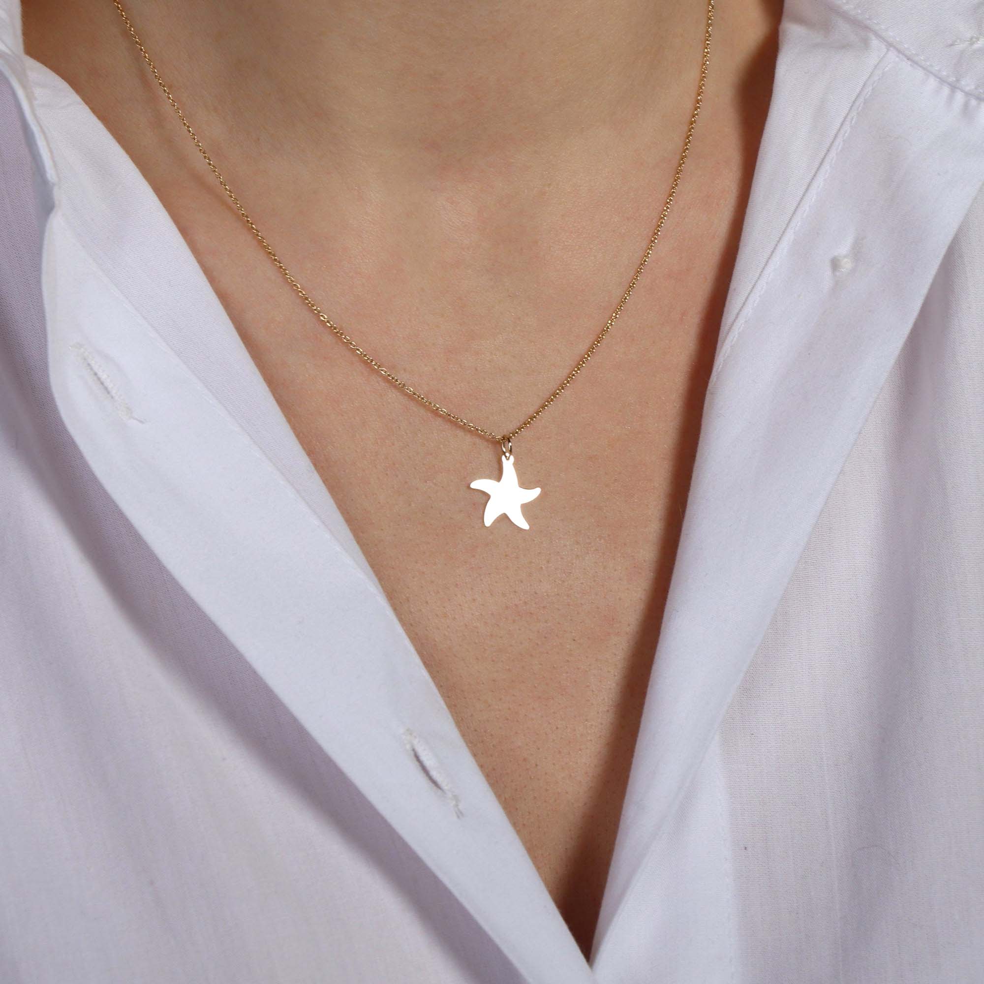 Starfish pendant necklace on a person's neck with a light background