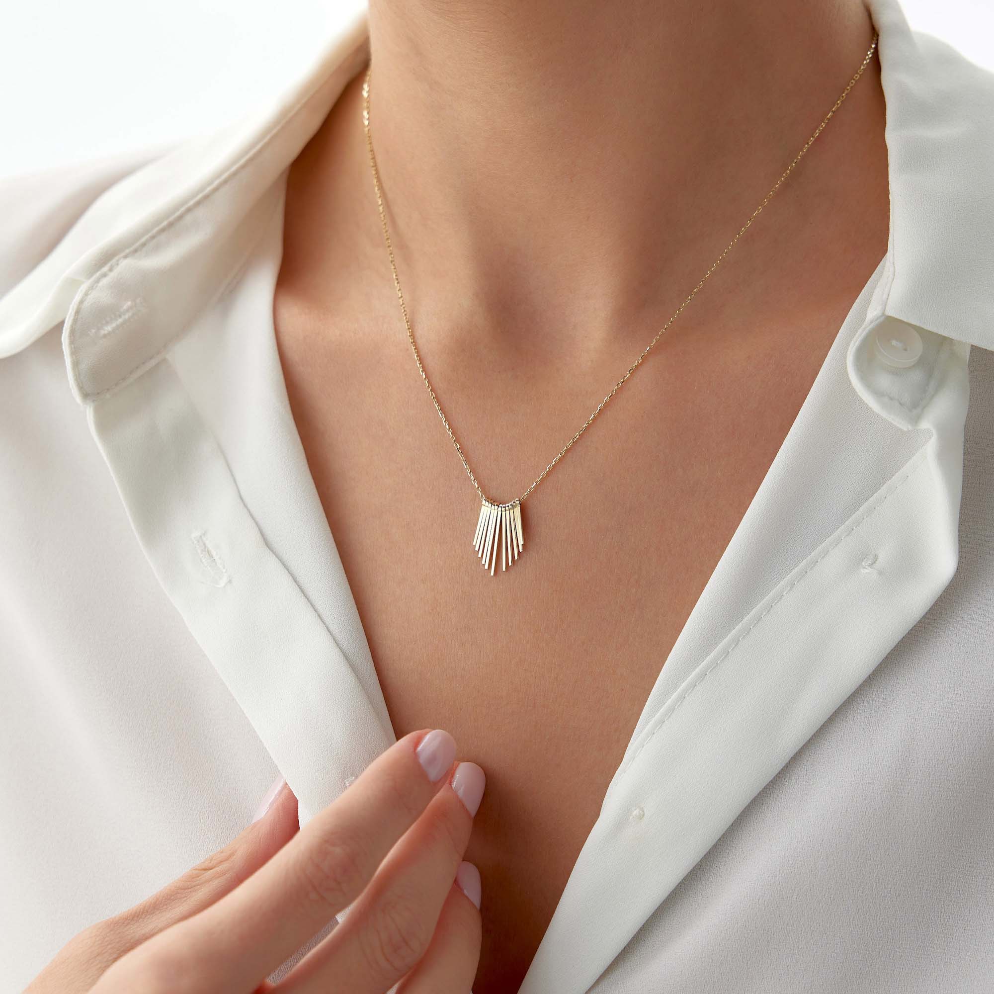 A 14k yellow gold necklace with spike charms together creating the illusion of a sunrise on a model's neck.