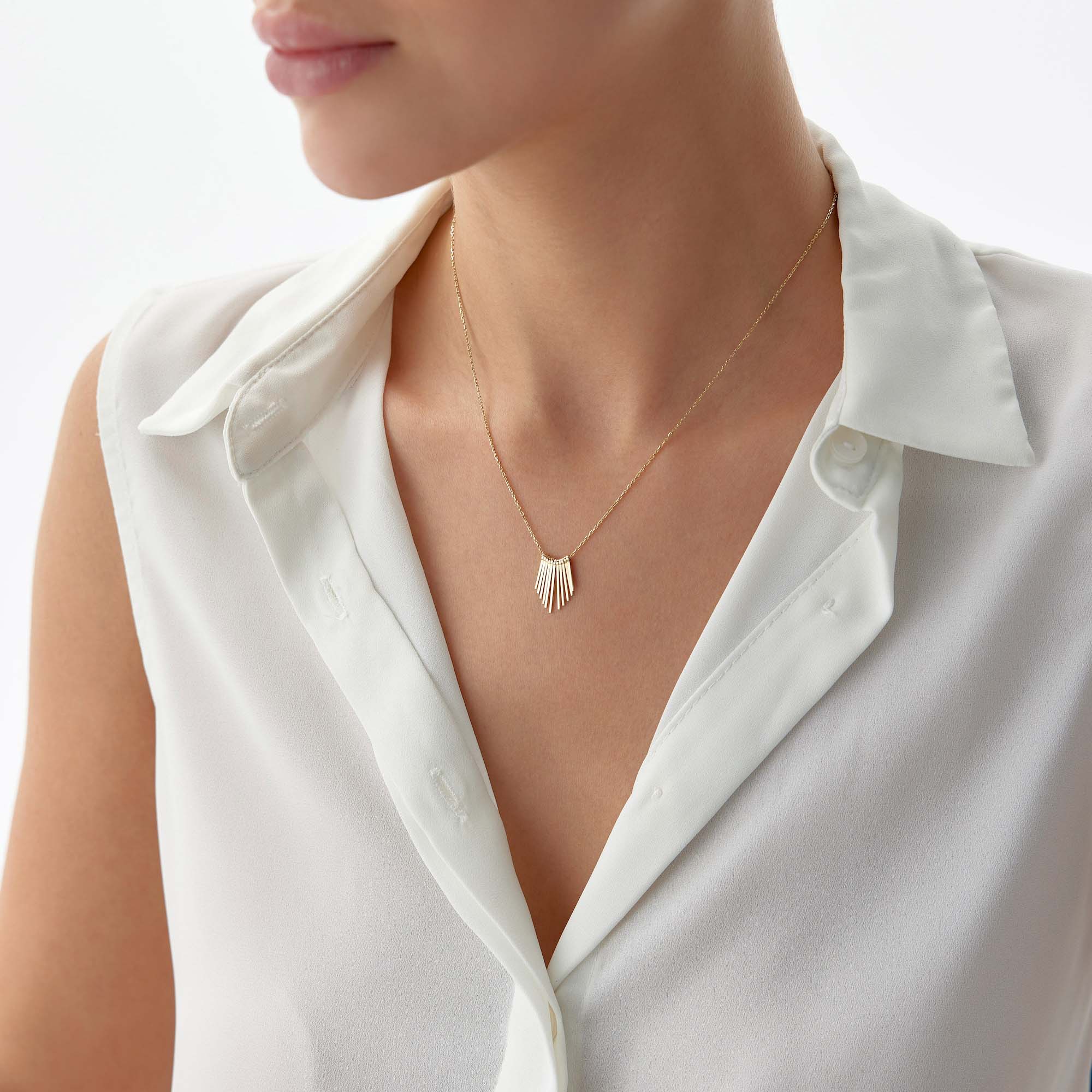 A 14k yellow gold necklace with spike charms together creating the illusion of a sunrise on a model's neck.