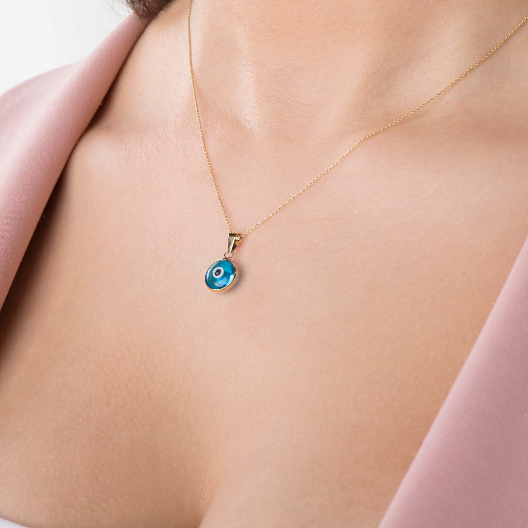A model wearing a translucent blue evil eye pendant on a chain