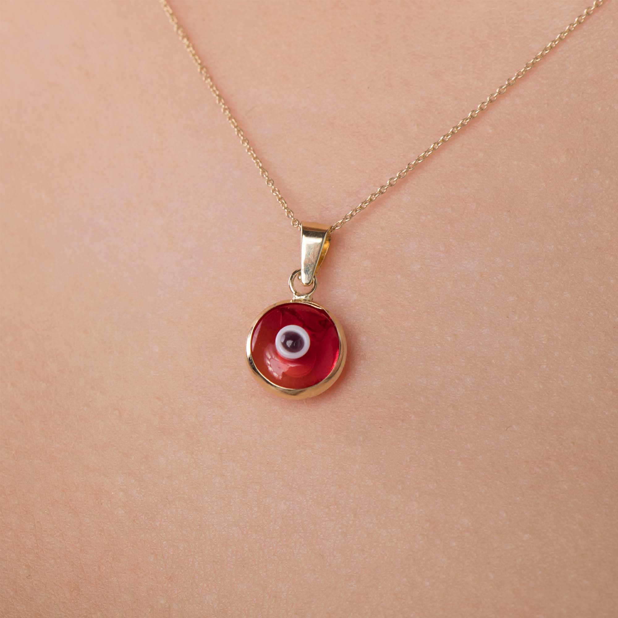 A 14k yellow gold translucent red evil eye pendant on a chain