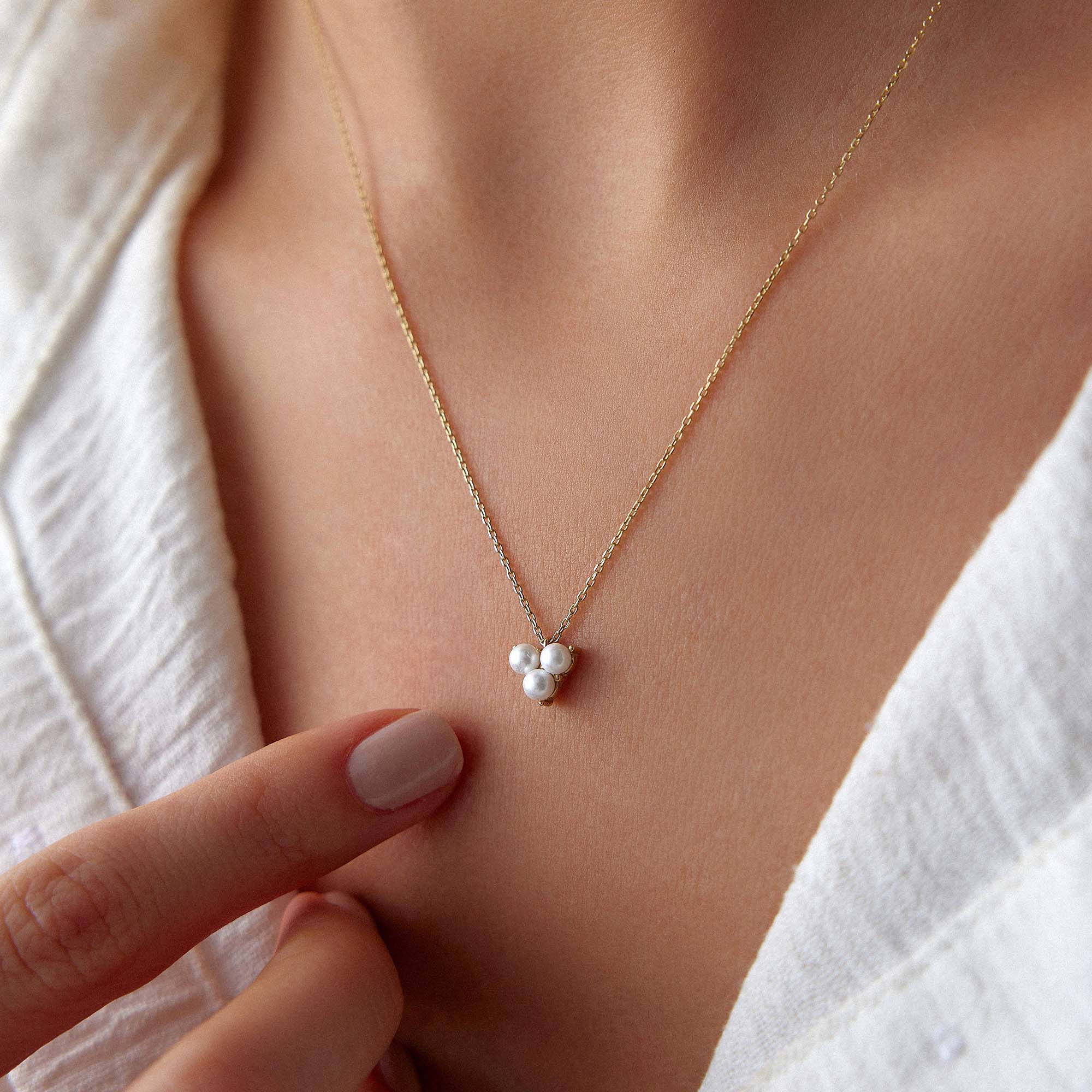 Gold necklace with a pearl pendant on a person's neck