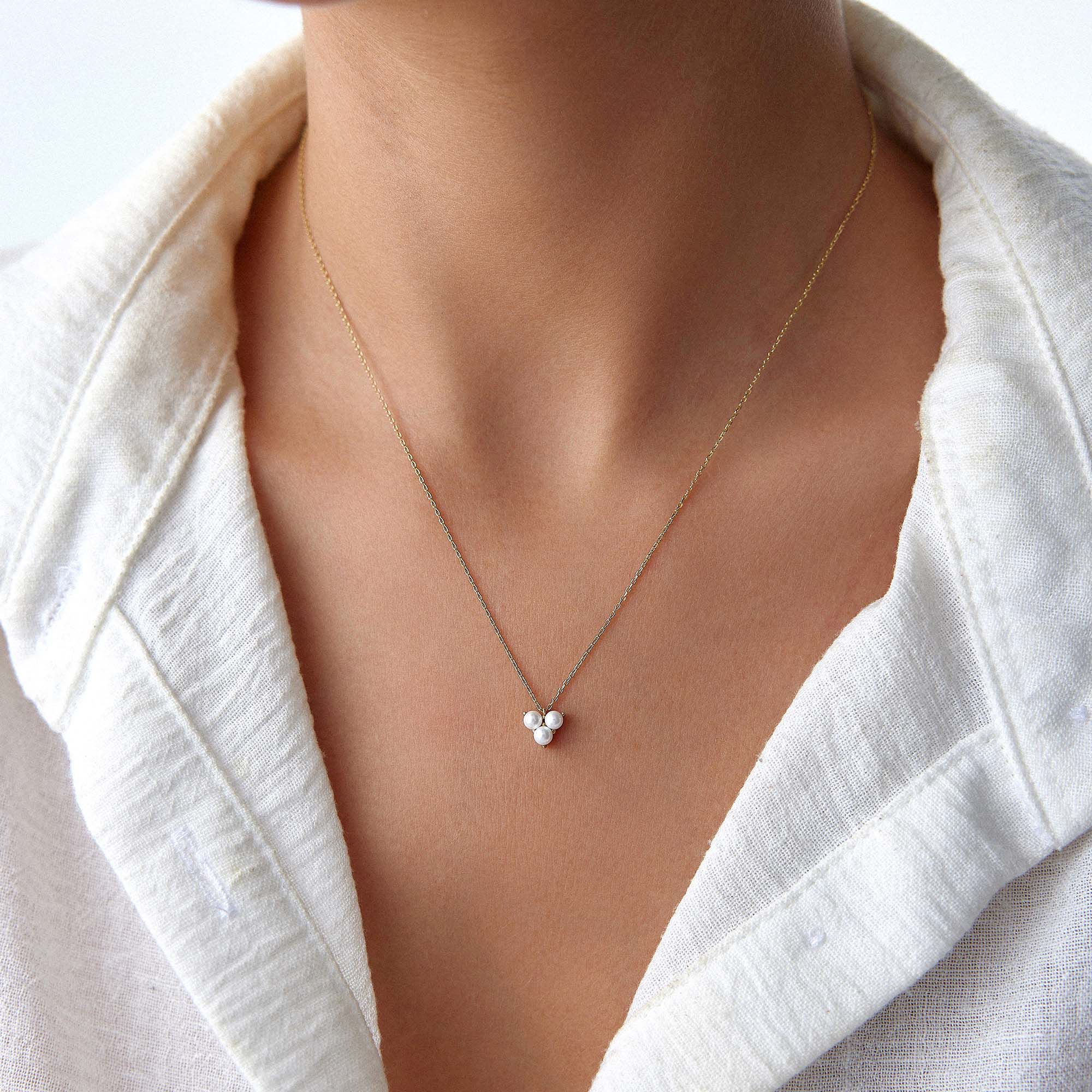 Gold necklace with a pearl pendant on a person's neck