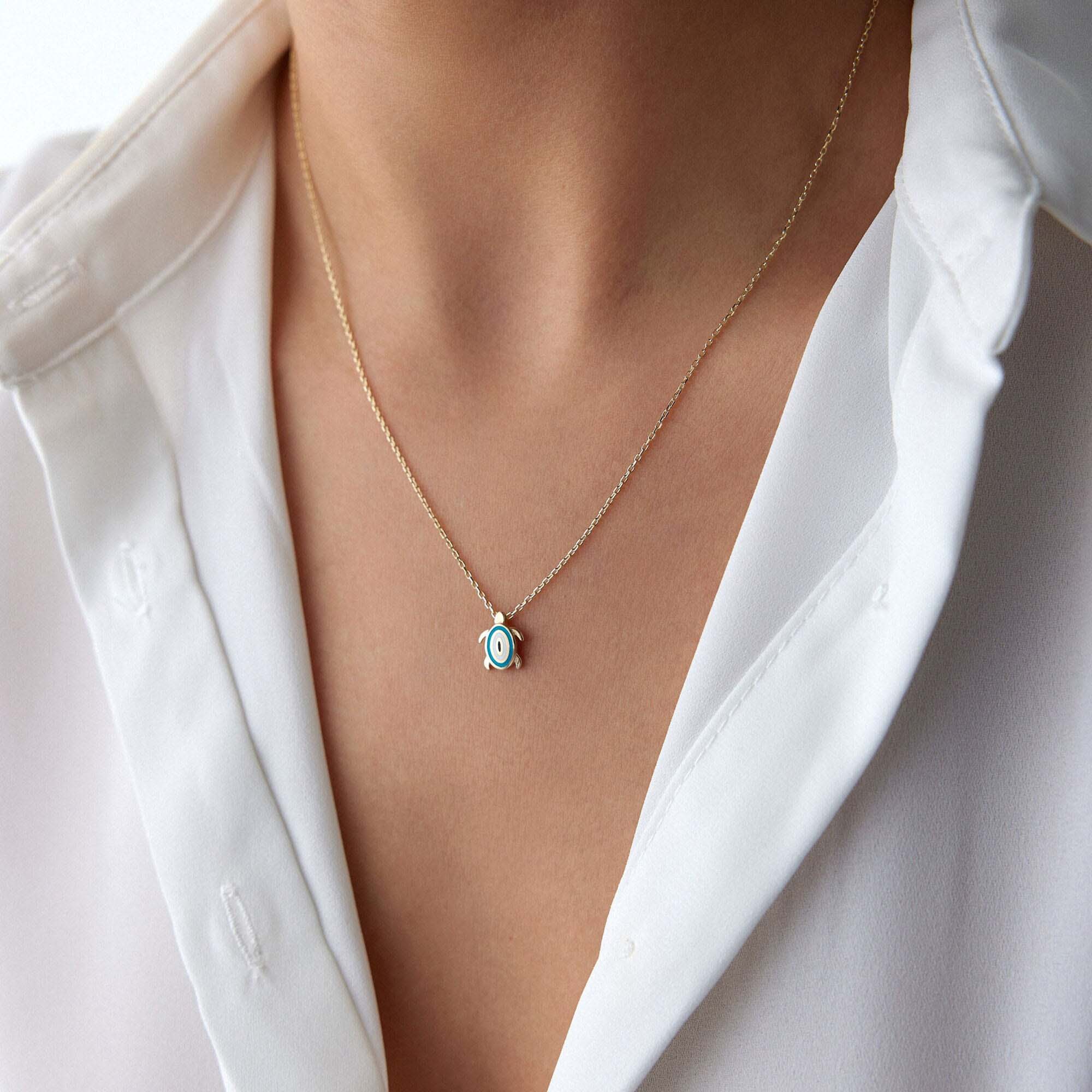 An upclose picture of a model wearing a turtle necklace with an evil eye motive at its back.