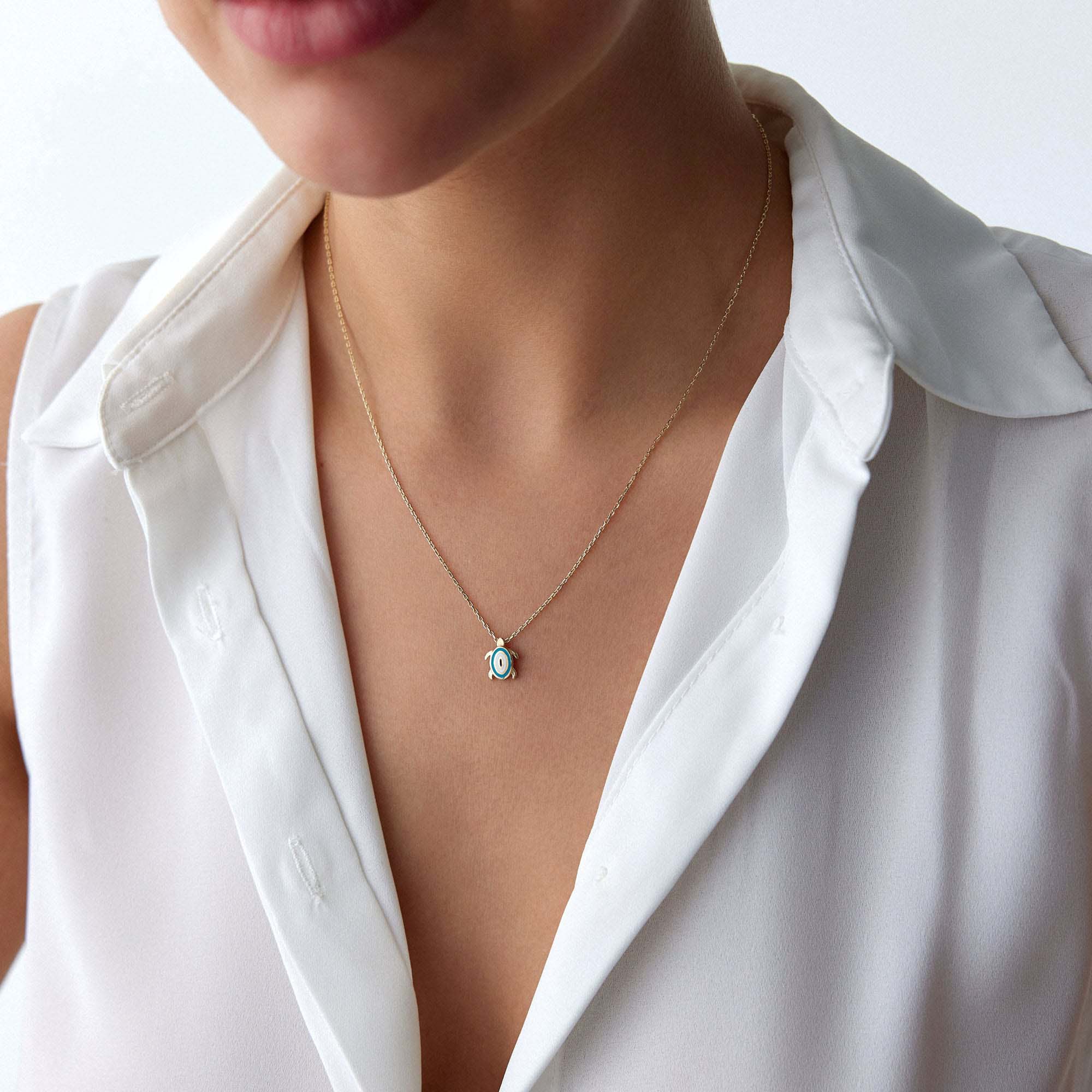 An upclose picture of a model wearing a turtle necklace with an evil eye motive at its back.
