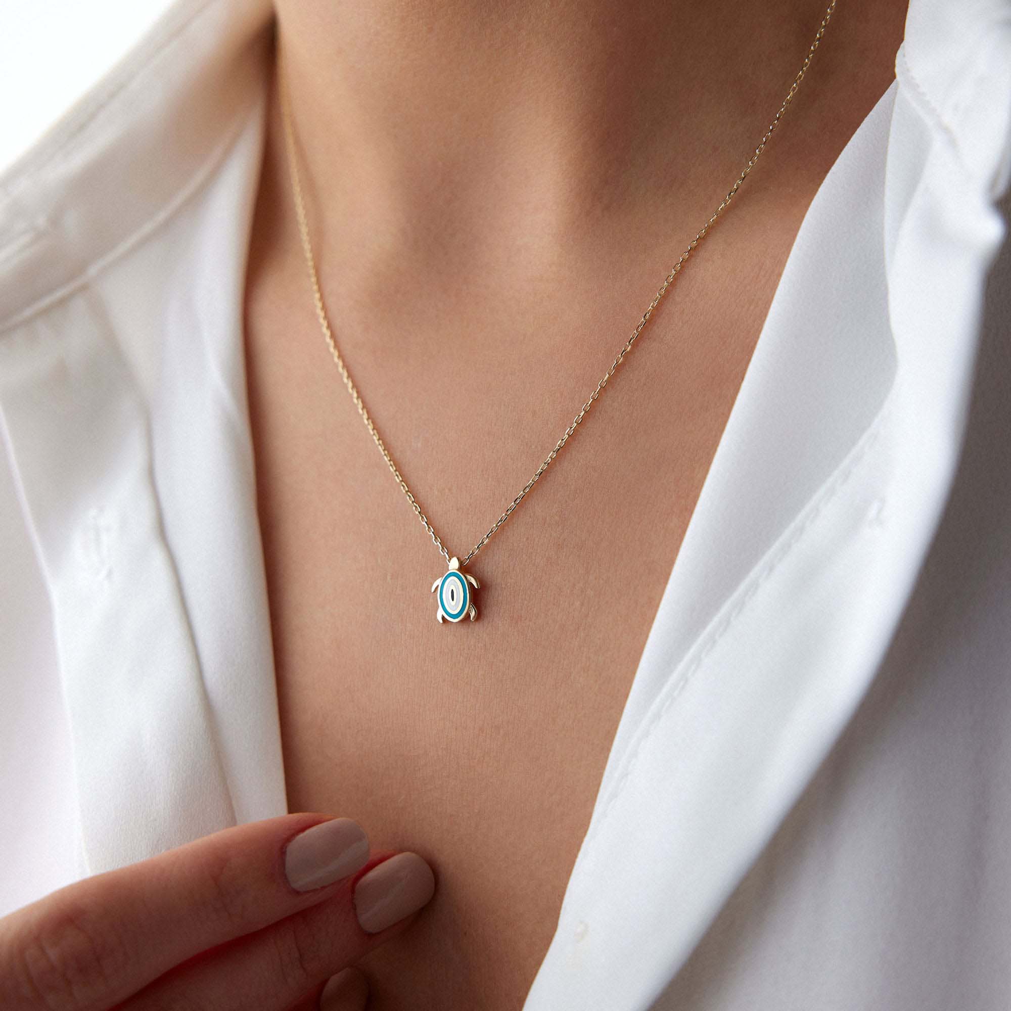 An upclose picture of a model wearing a turtle necklace with an evil eye motive at its back.