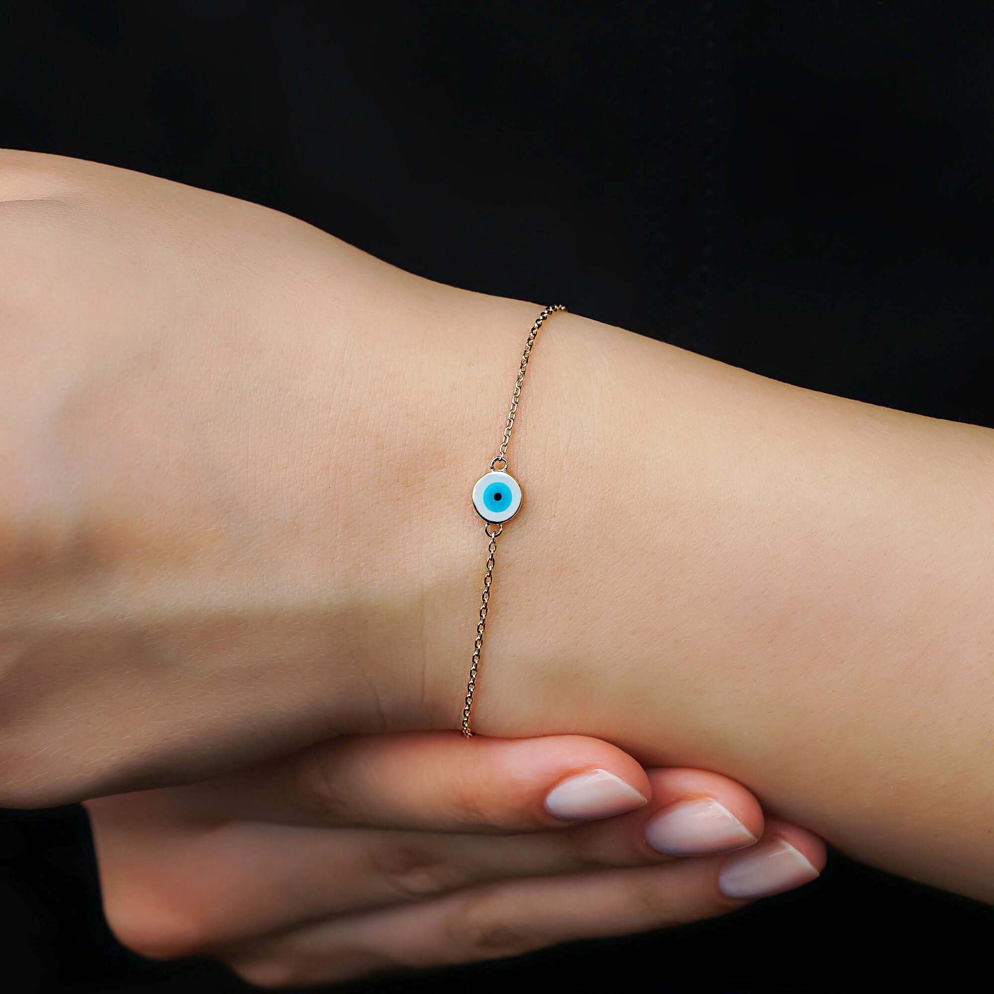 14k yellow gold white evil eye bracelet shown on a wrist.