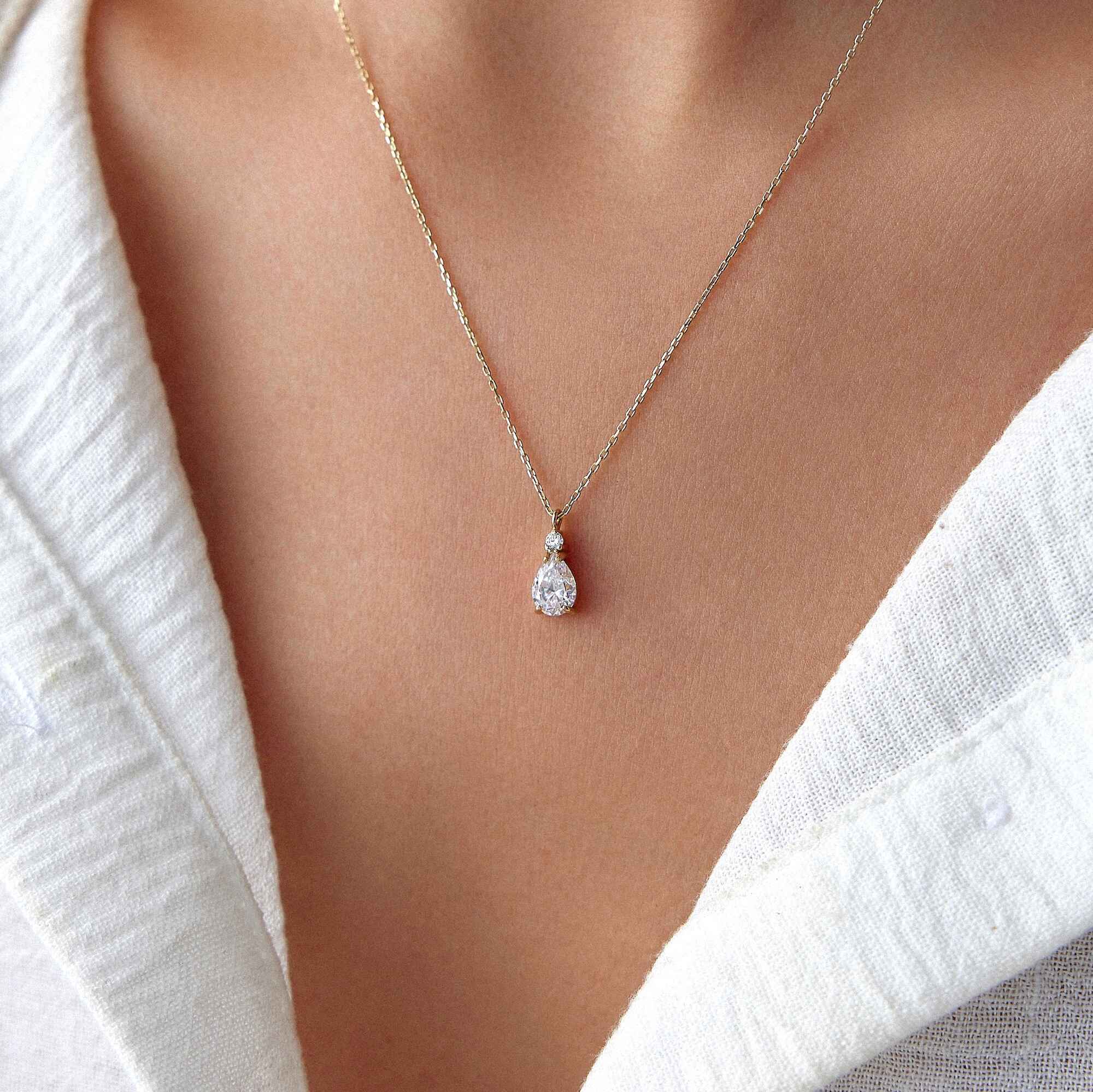 A 14k yellow gold white drop necklace worn by a model