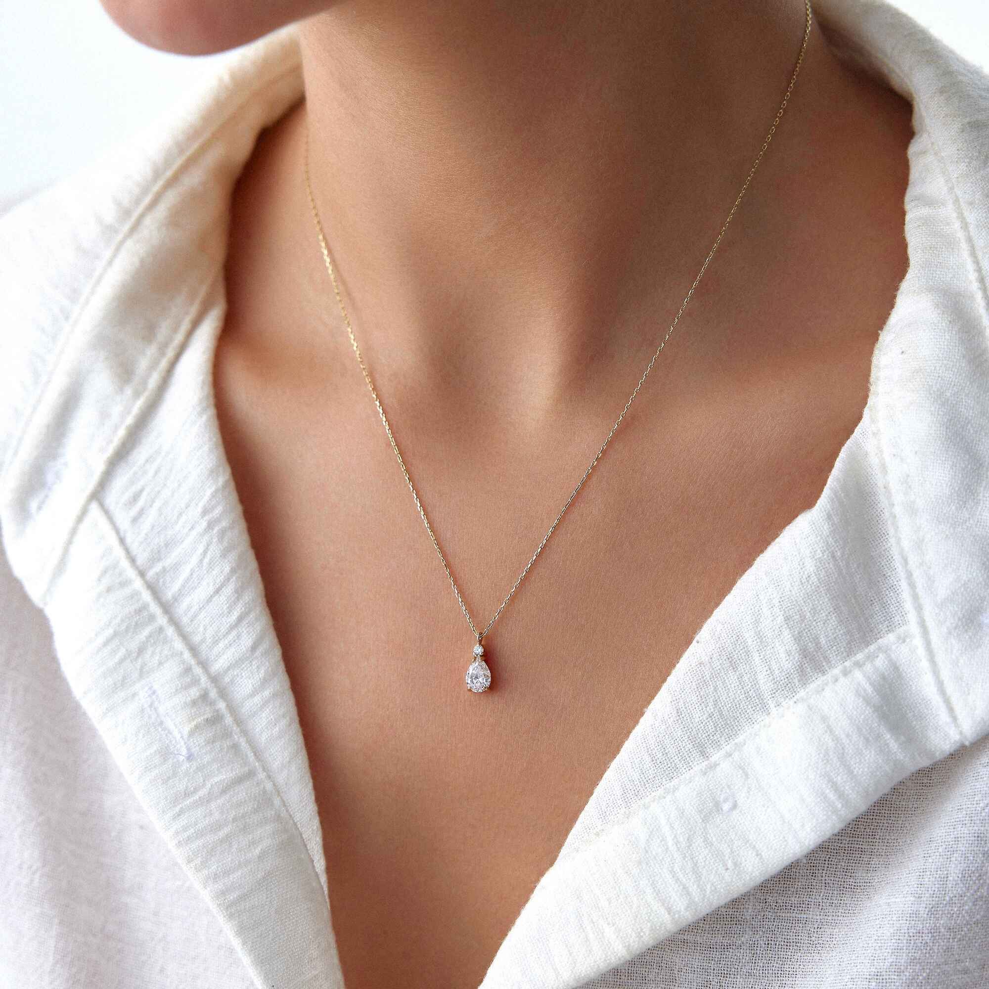 A 14k yellow gold white drop necklace worn by a model