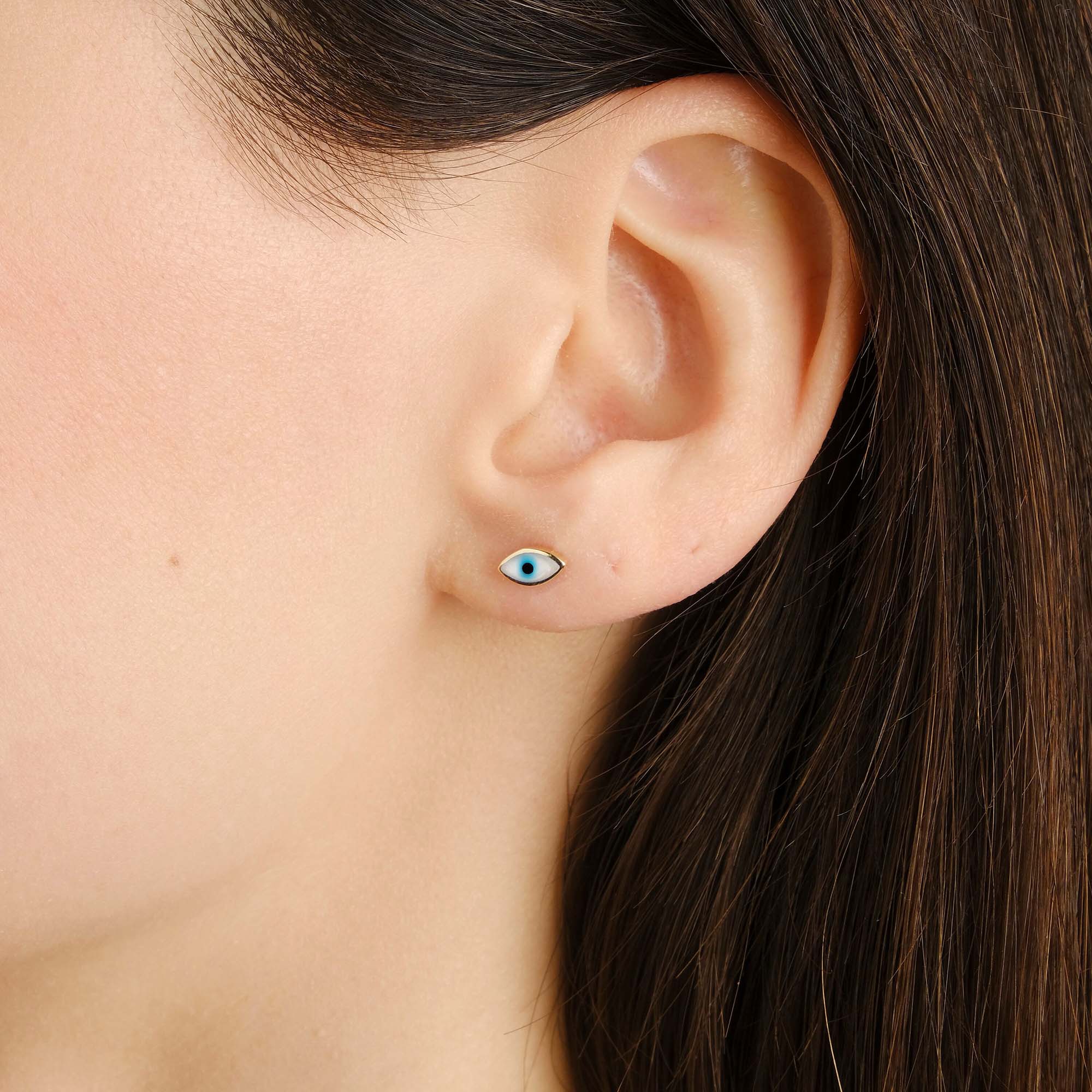 Close-up of an ear wearing a blue eye-shaped stud earring.